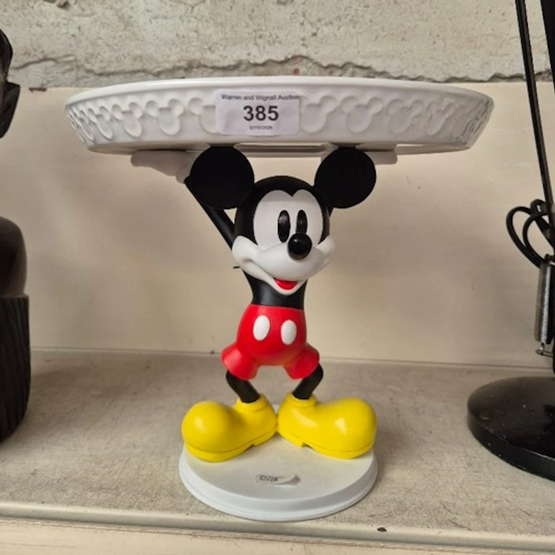 A Disney Store cake plate being held aloft by a Mickey Mouse...