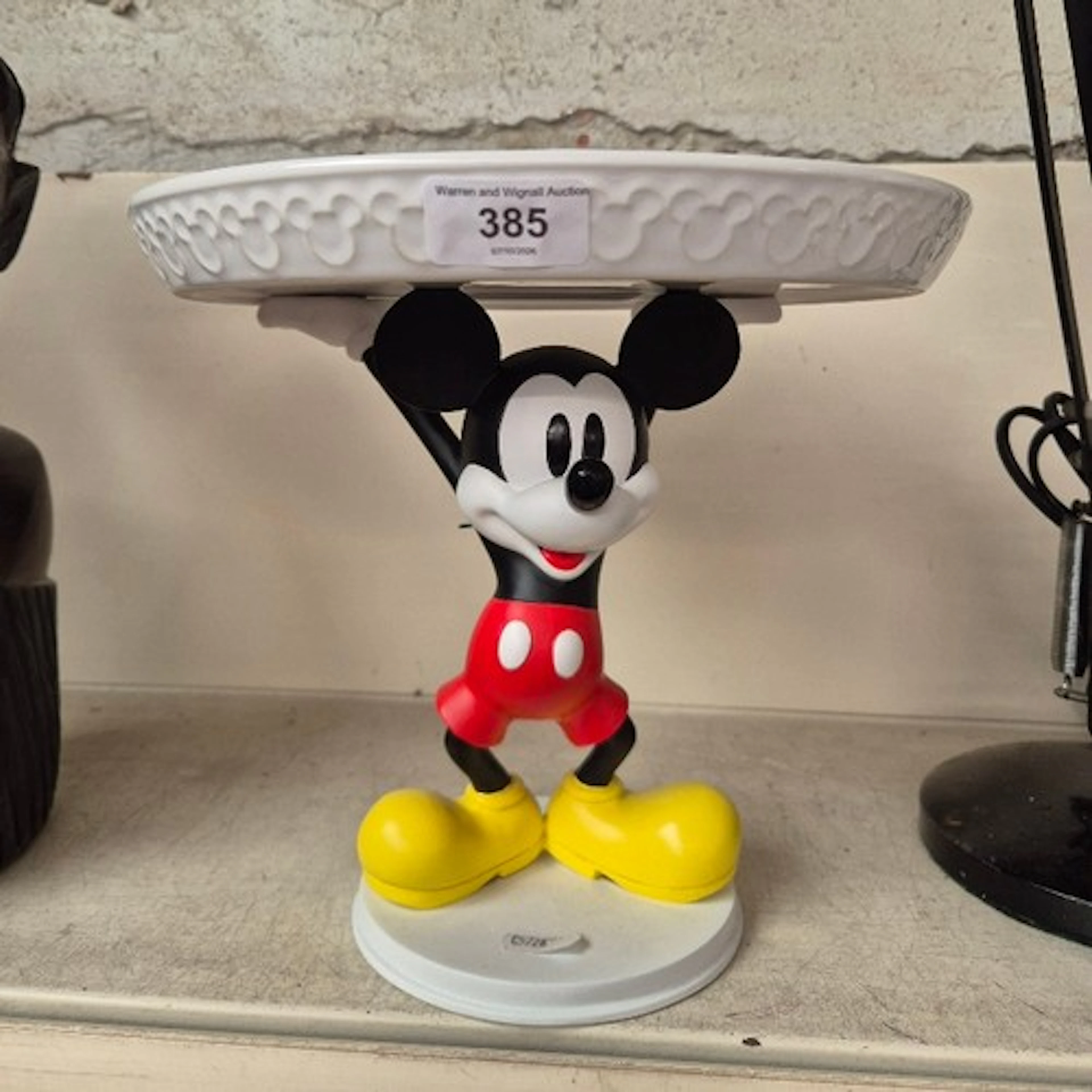 A Disney Store cake plate being held aloft by a Mickey Mouse...