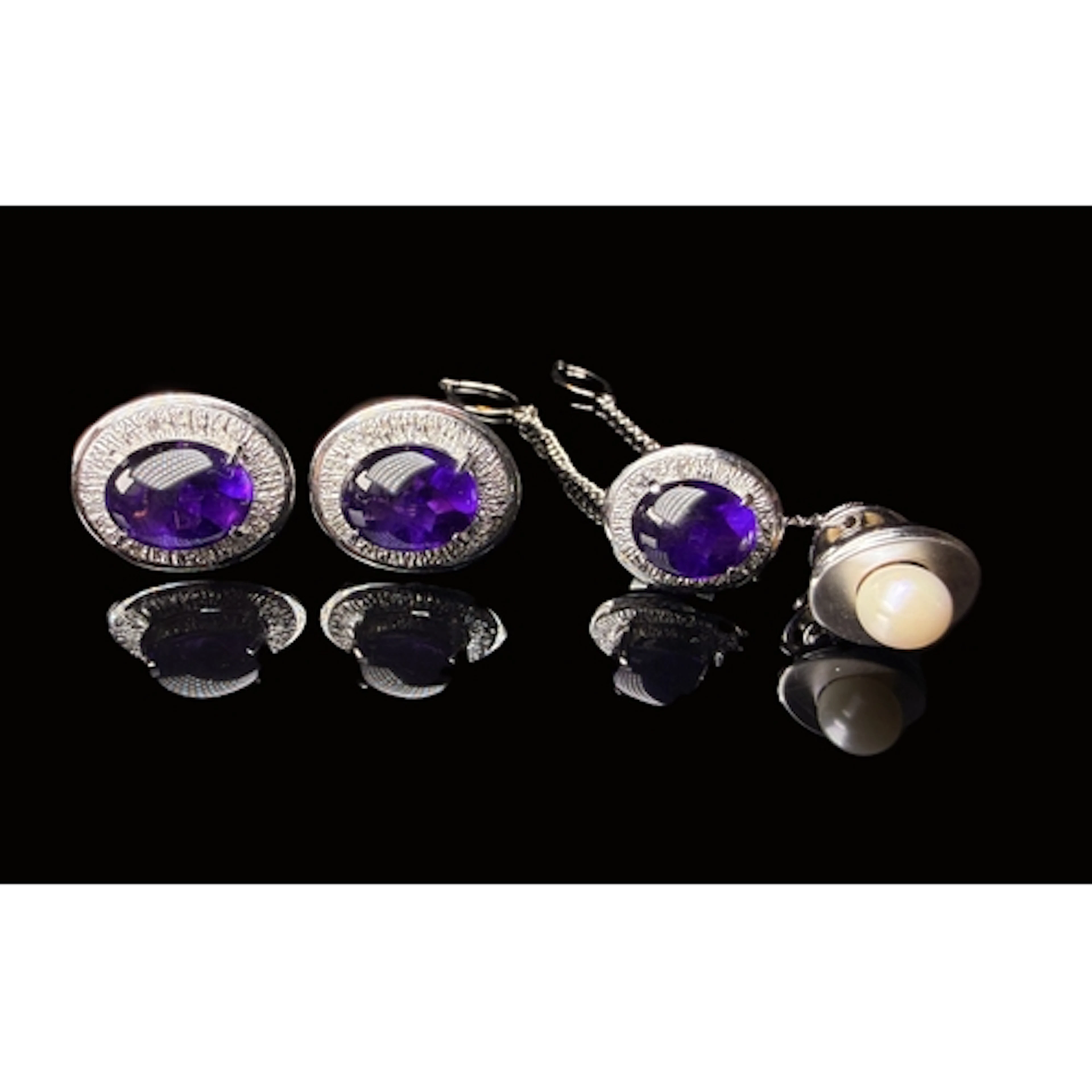 A white metal set of cufflinks and tie pin, each with centra...