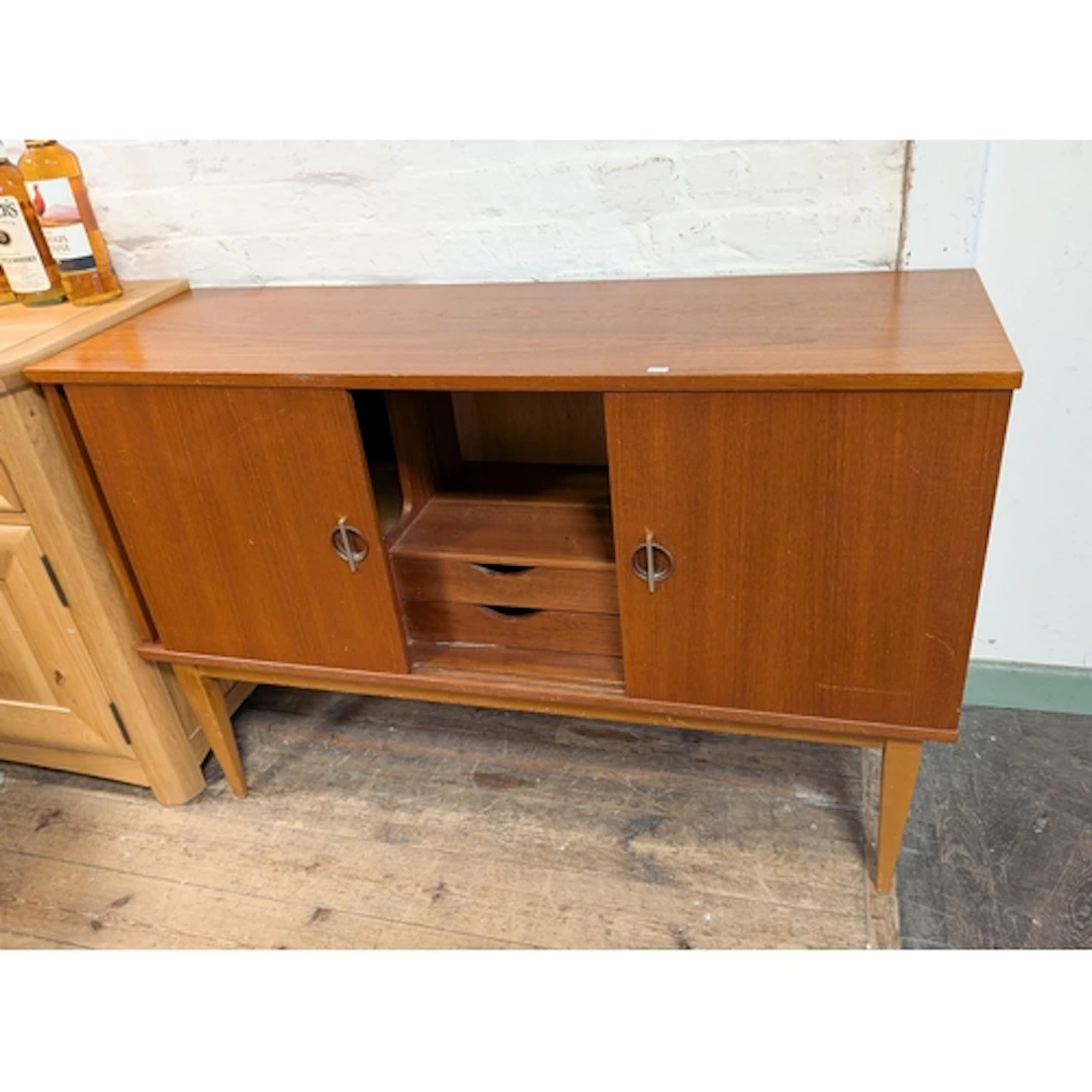 A 1970's teak sideboard with sliding doors, drawers fitted ...
