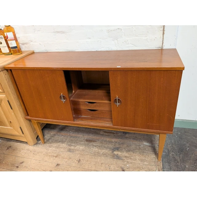 A 1970's teak sideboard with sliding doors, drawers fitted ...