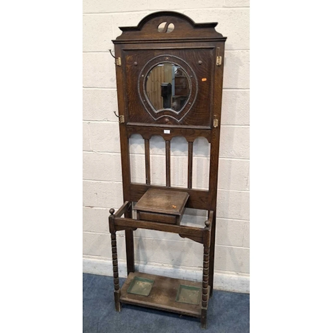 AN EARLY 20TH CENTURY OAK HALL STAND, with a bevelled mirror...
