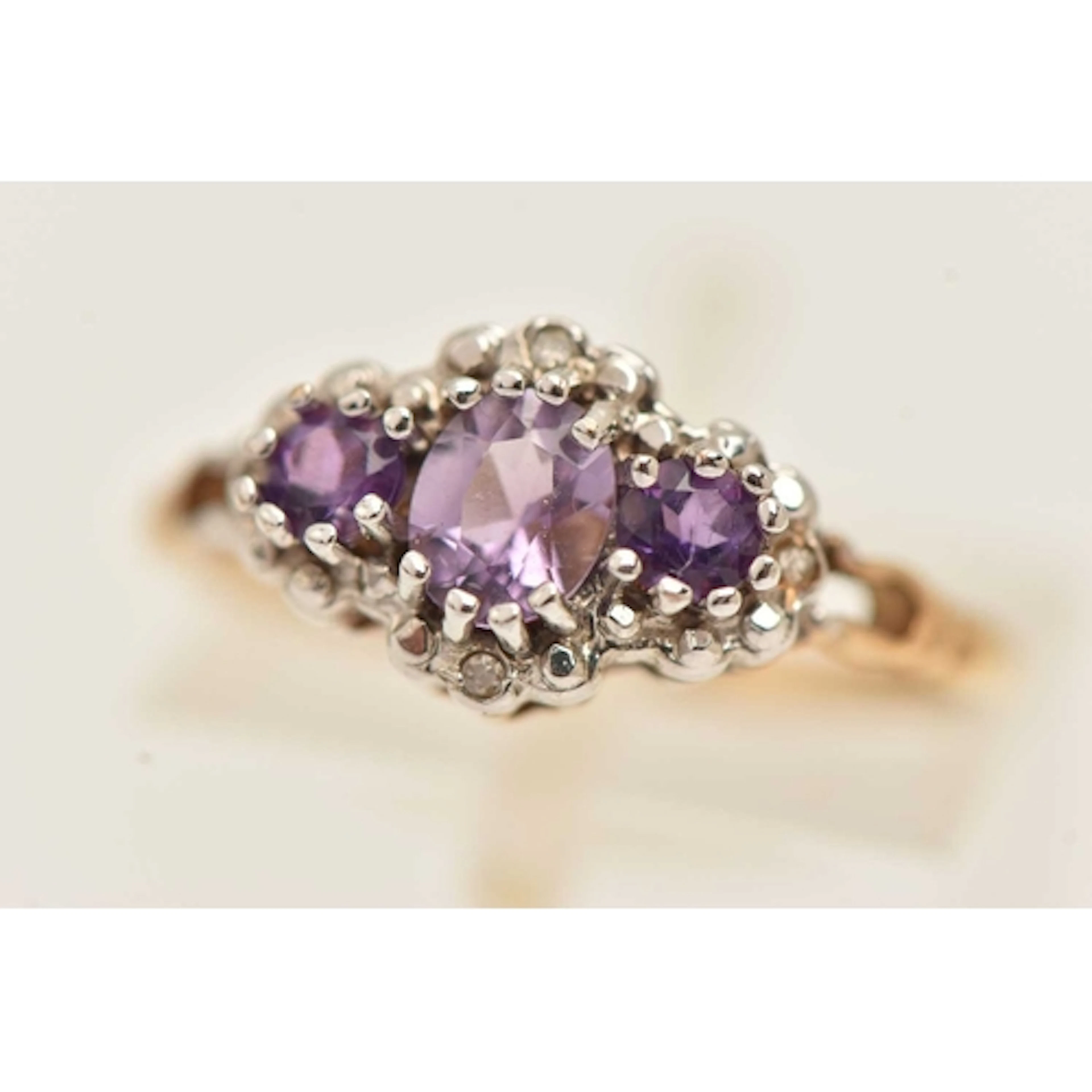 A 9CT GOLD GEM SET RING, designed as three circular cut amet...