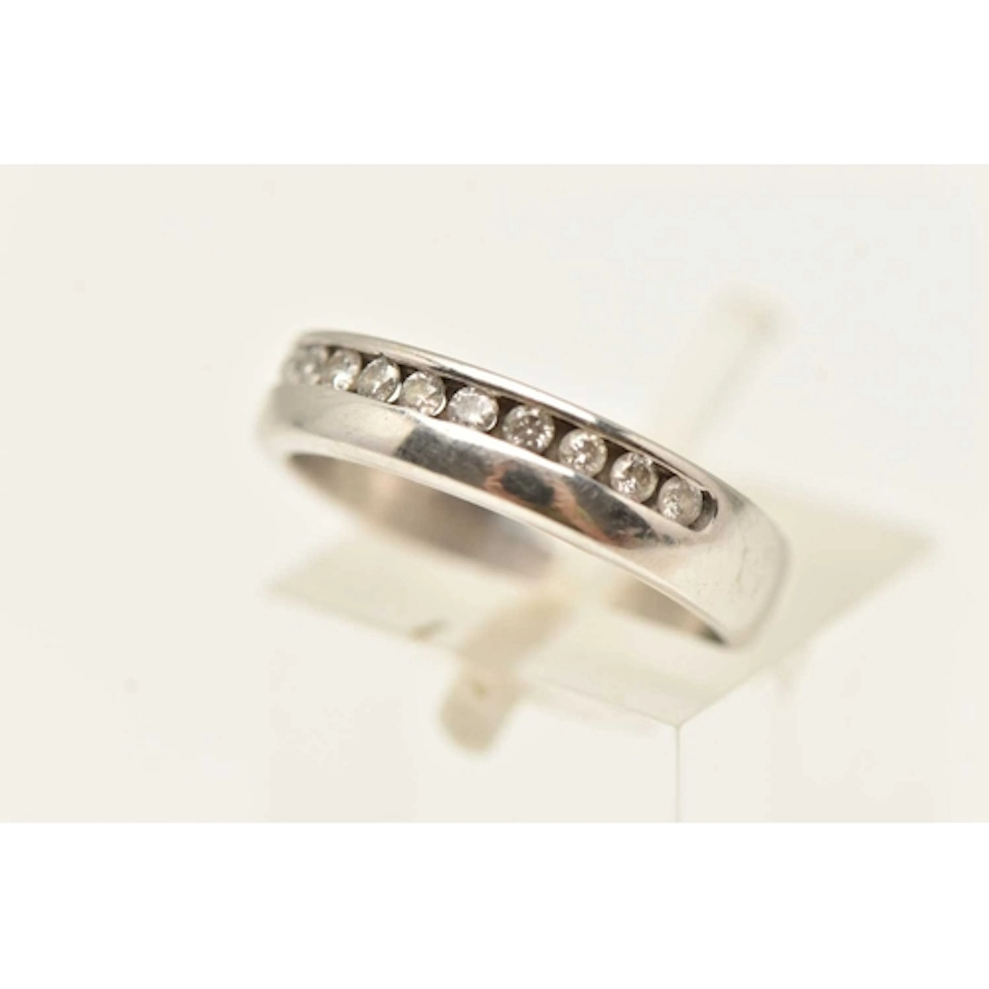 AN 18CT WHITE GOLD BAND RING, channel set with twelve round ...