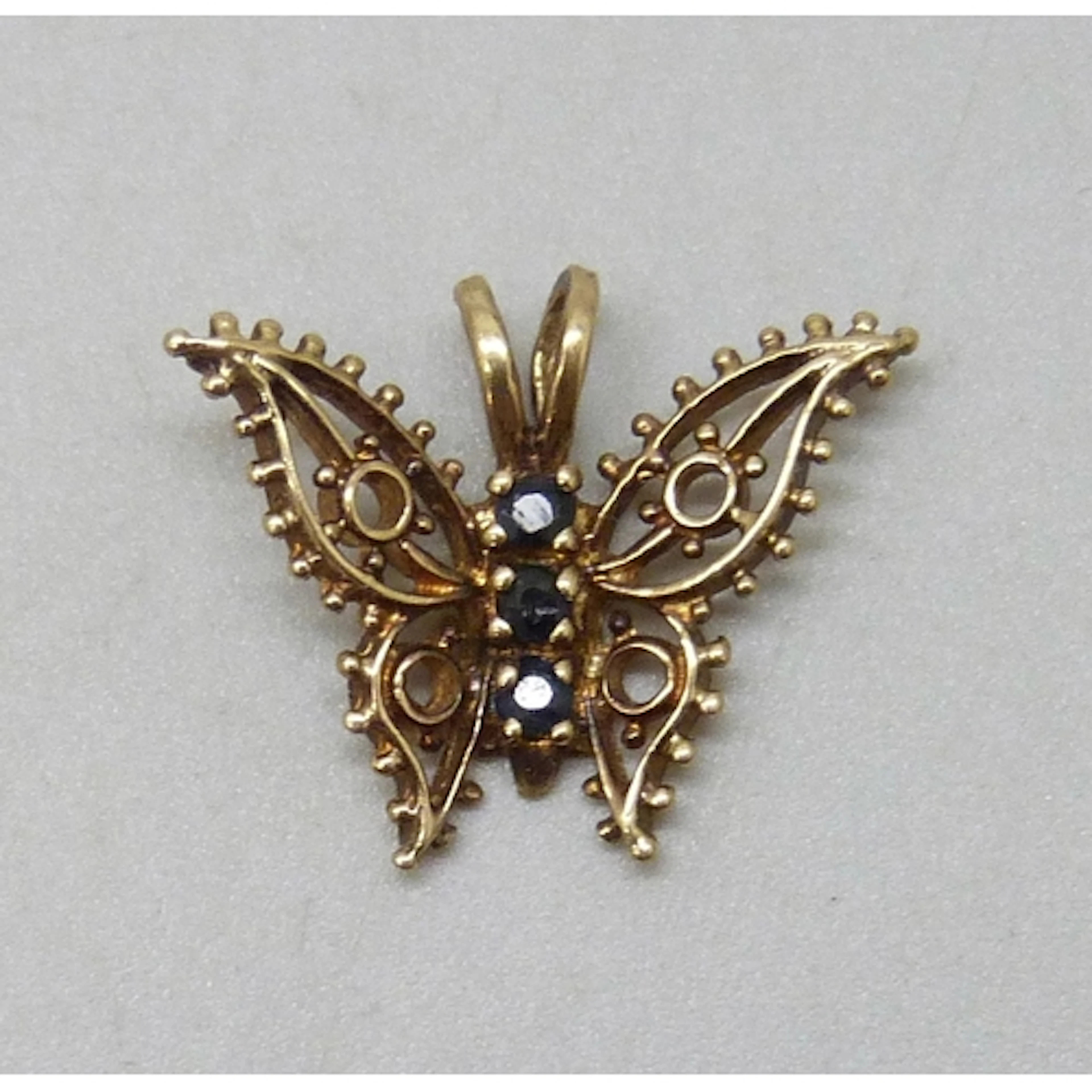 A yellow metal and sapphire butterfly design pendant, 0.9g, ...