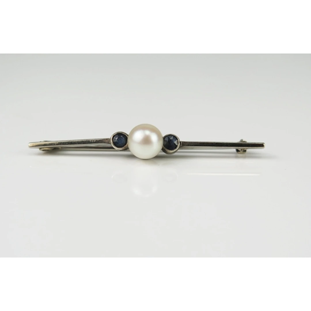 A sapphire and pearl or cultured pearl bar brooch in a preci...