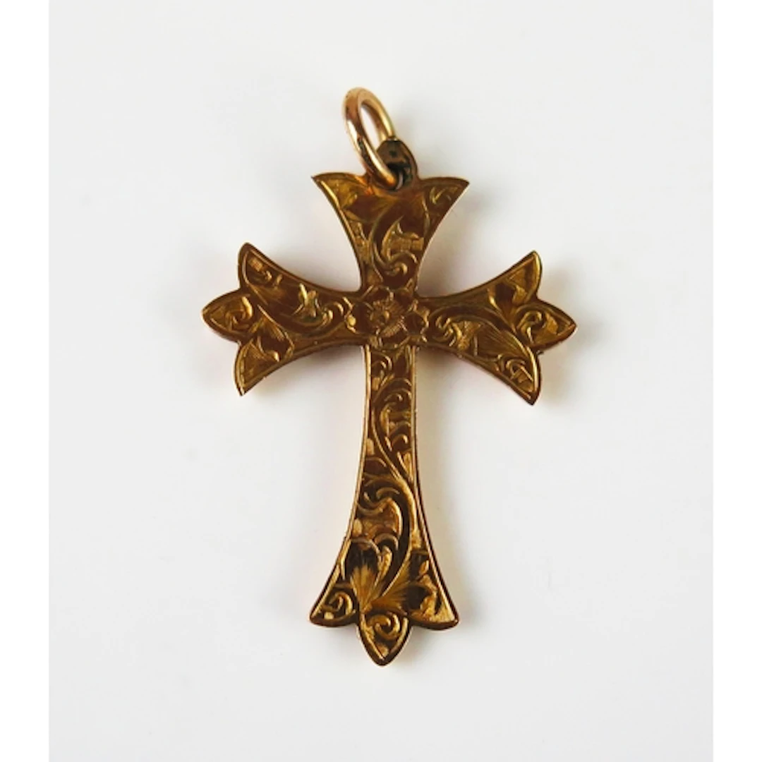 An antique 9ct gold cross pendant with chased foliate decora...