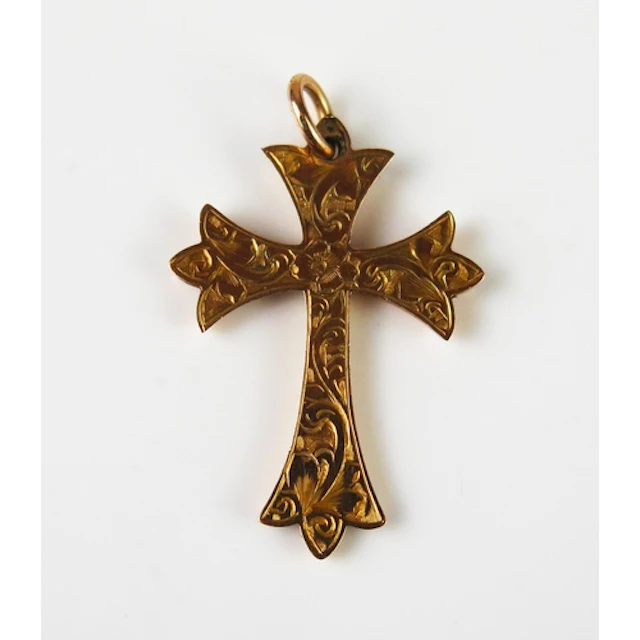 An antique 9ct gold cross pendant with chased foliate decora...