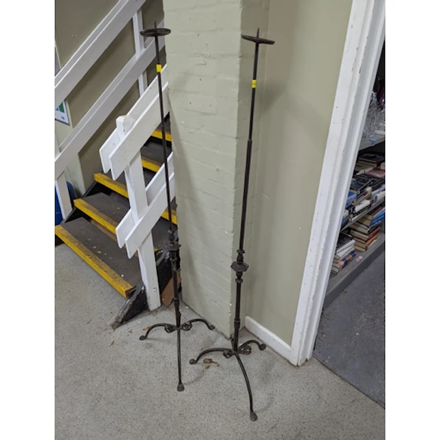 Two wrought iron floor standing pricket candleholders on tri...