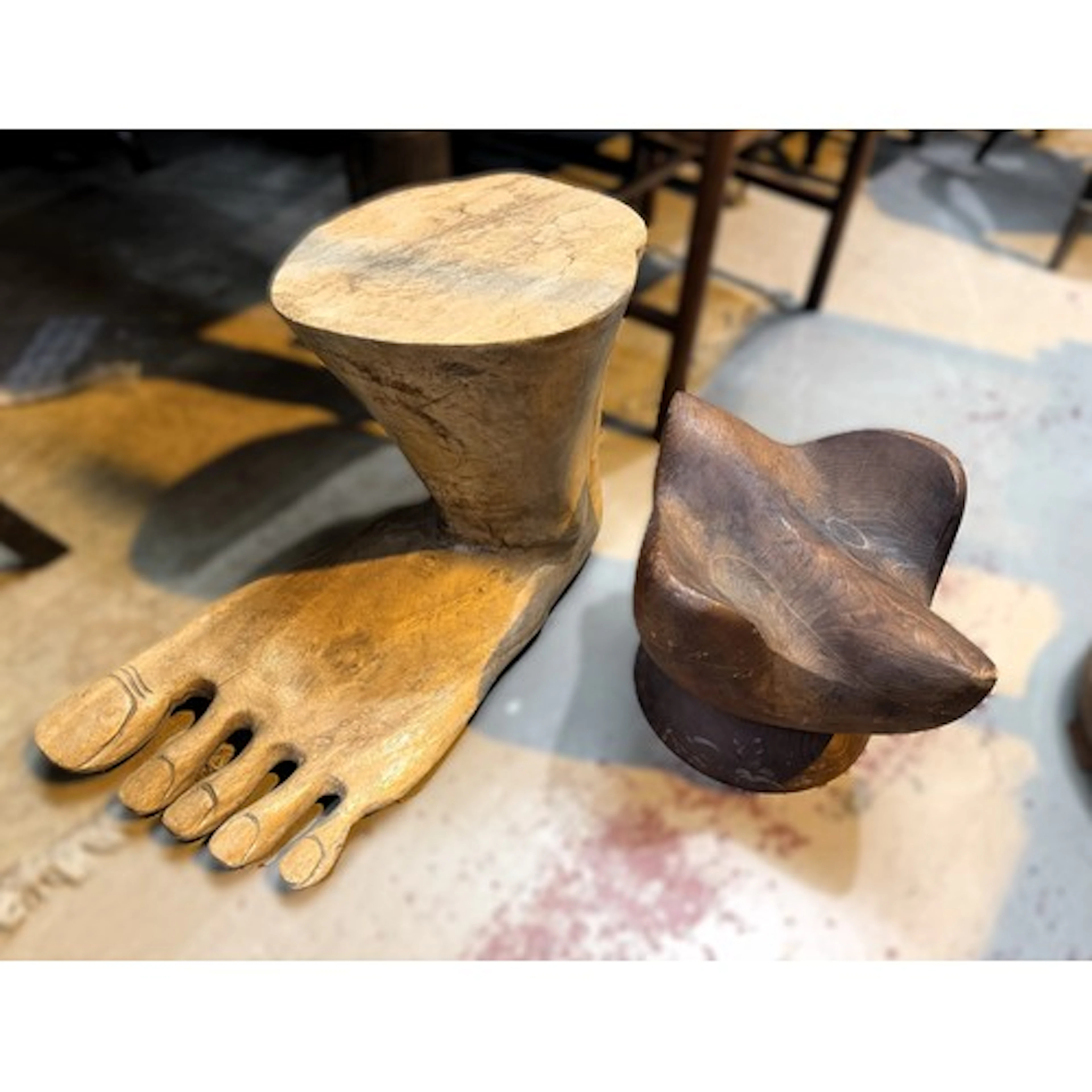 A stool in the form of a foot and a carved wooden sculpture.