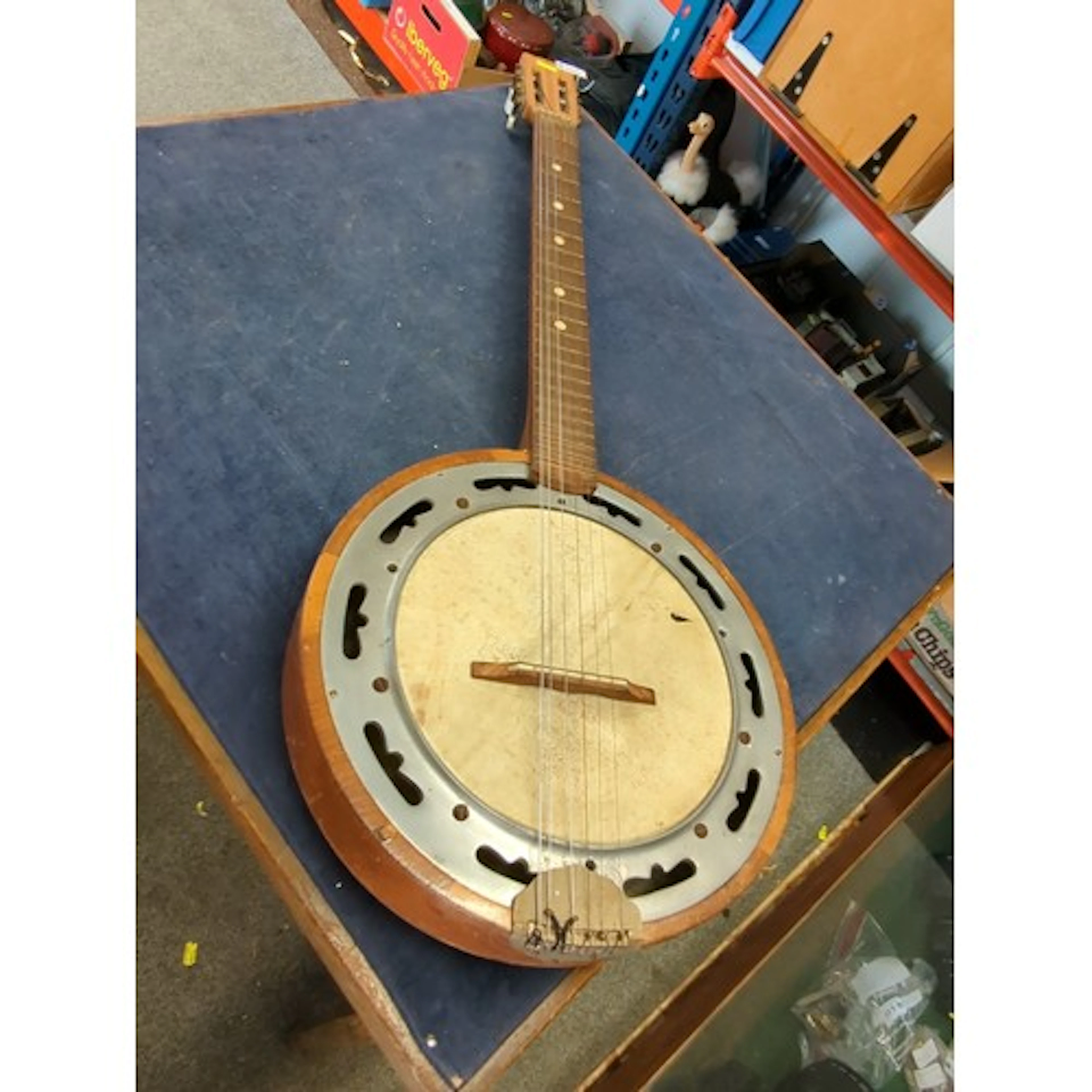 Six-string banjo with circular wooden rim, skin head and pie...