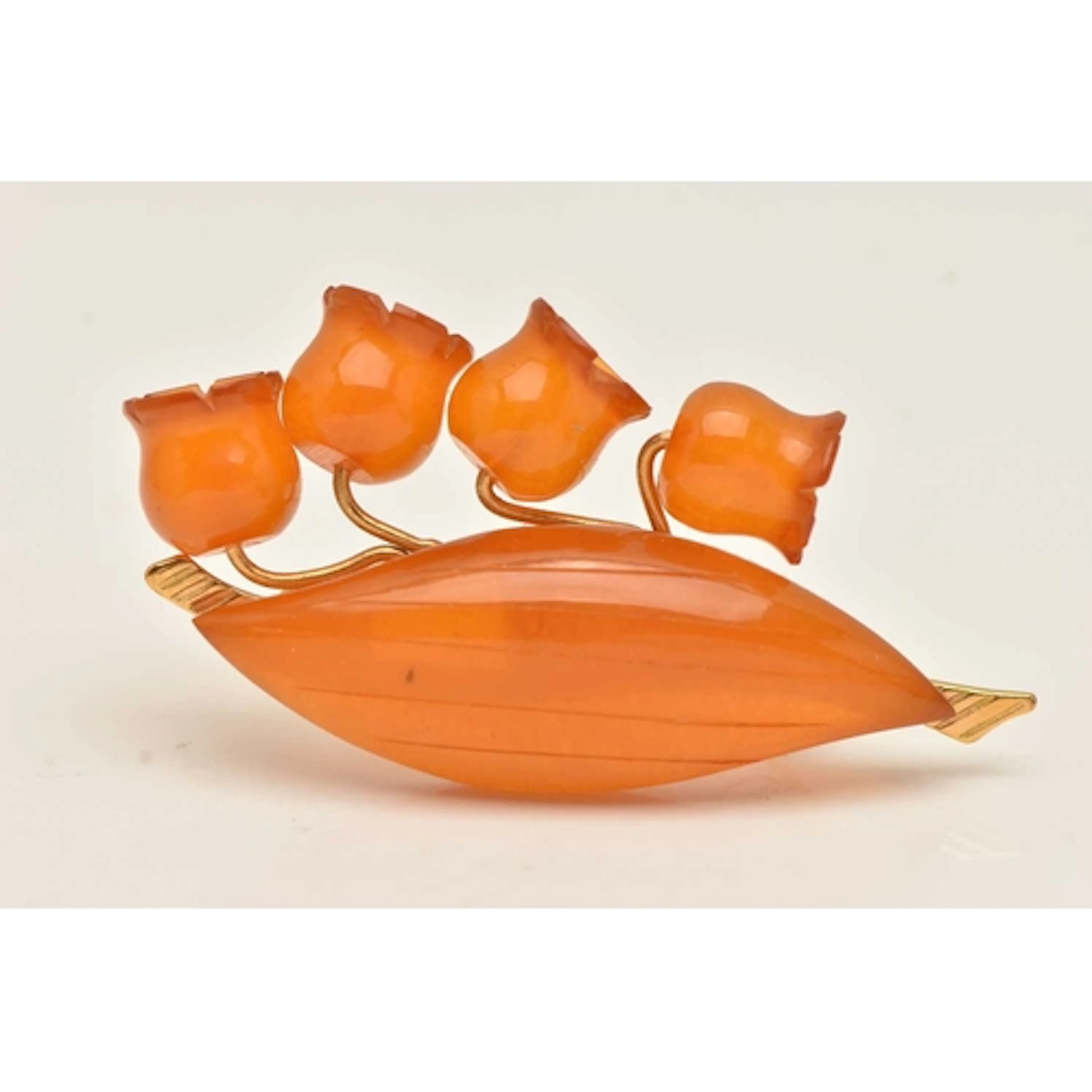A YELLOW METAL AMBER FLORAL BROOCH, carved and polished ambe...