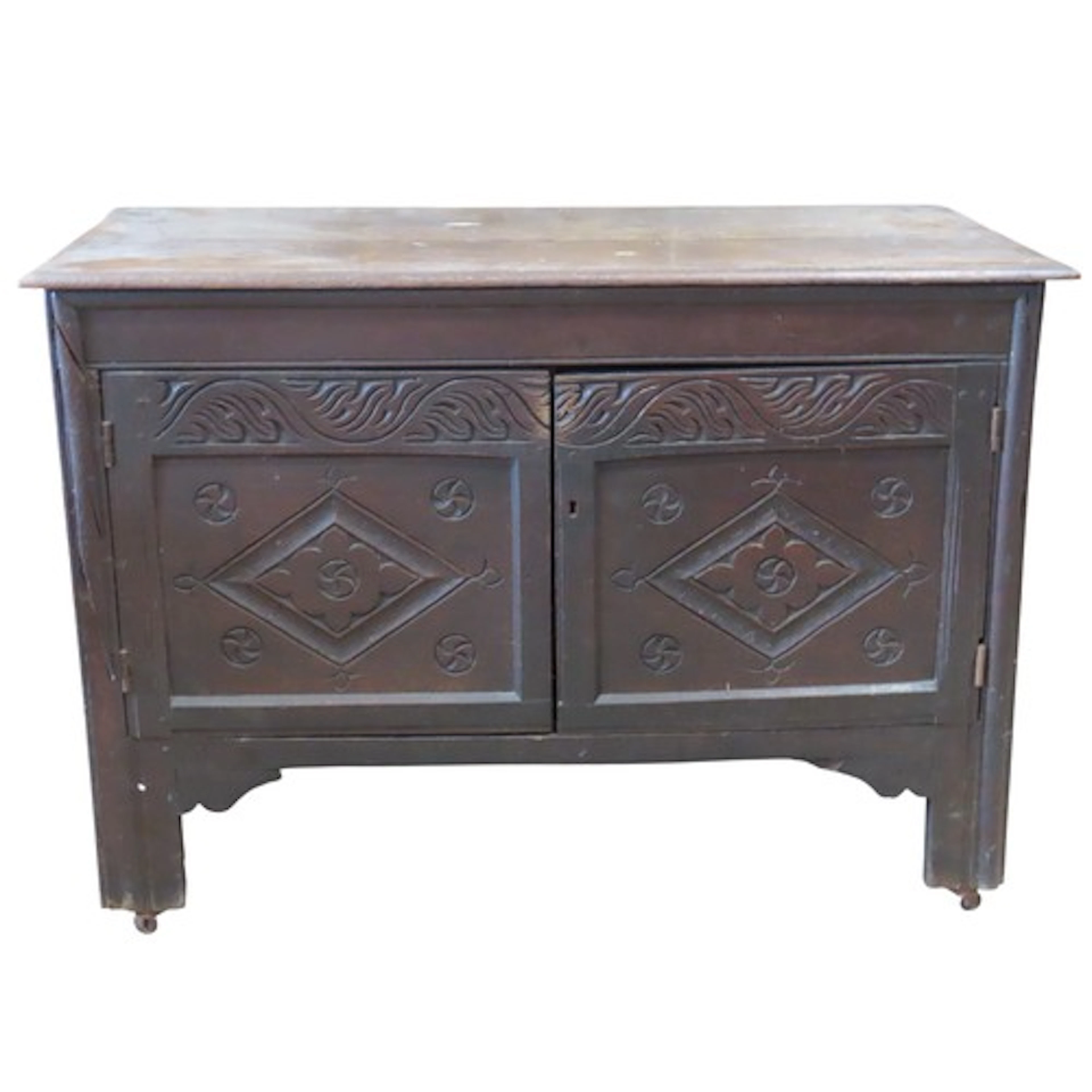 An antique oak side cupboard enclosed by a pair of carved pa...