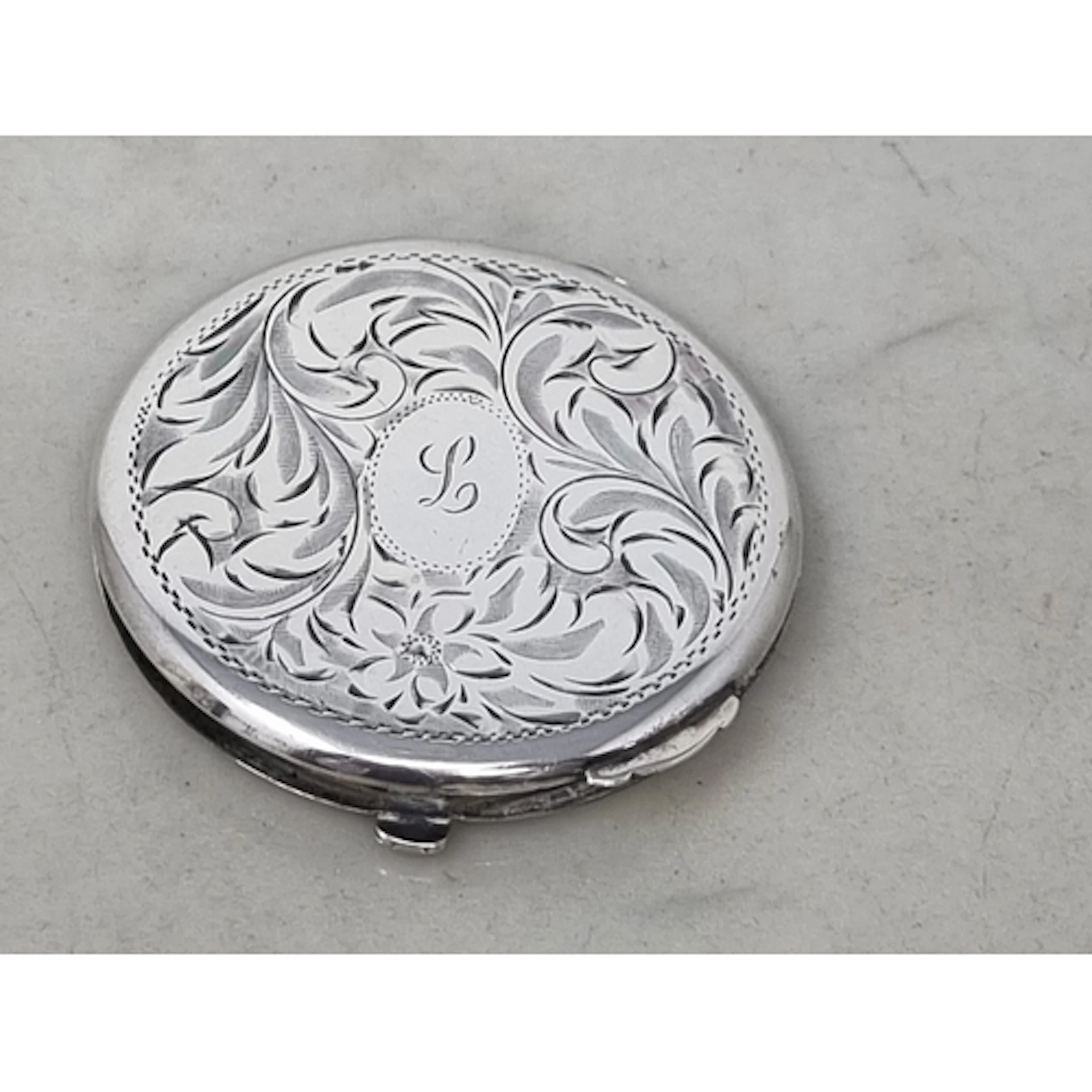A sterling silver circular Powder Compact with leafage scrol...