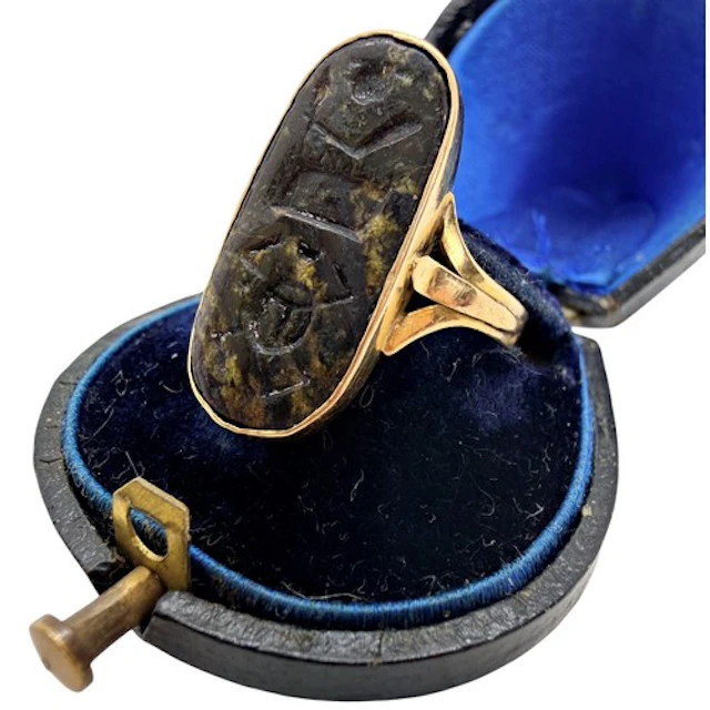 A gold ring set with an Egyptian hieroglyphic seal plaque, a...