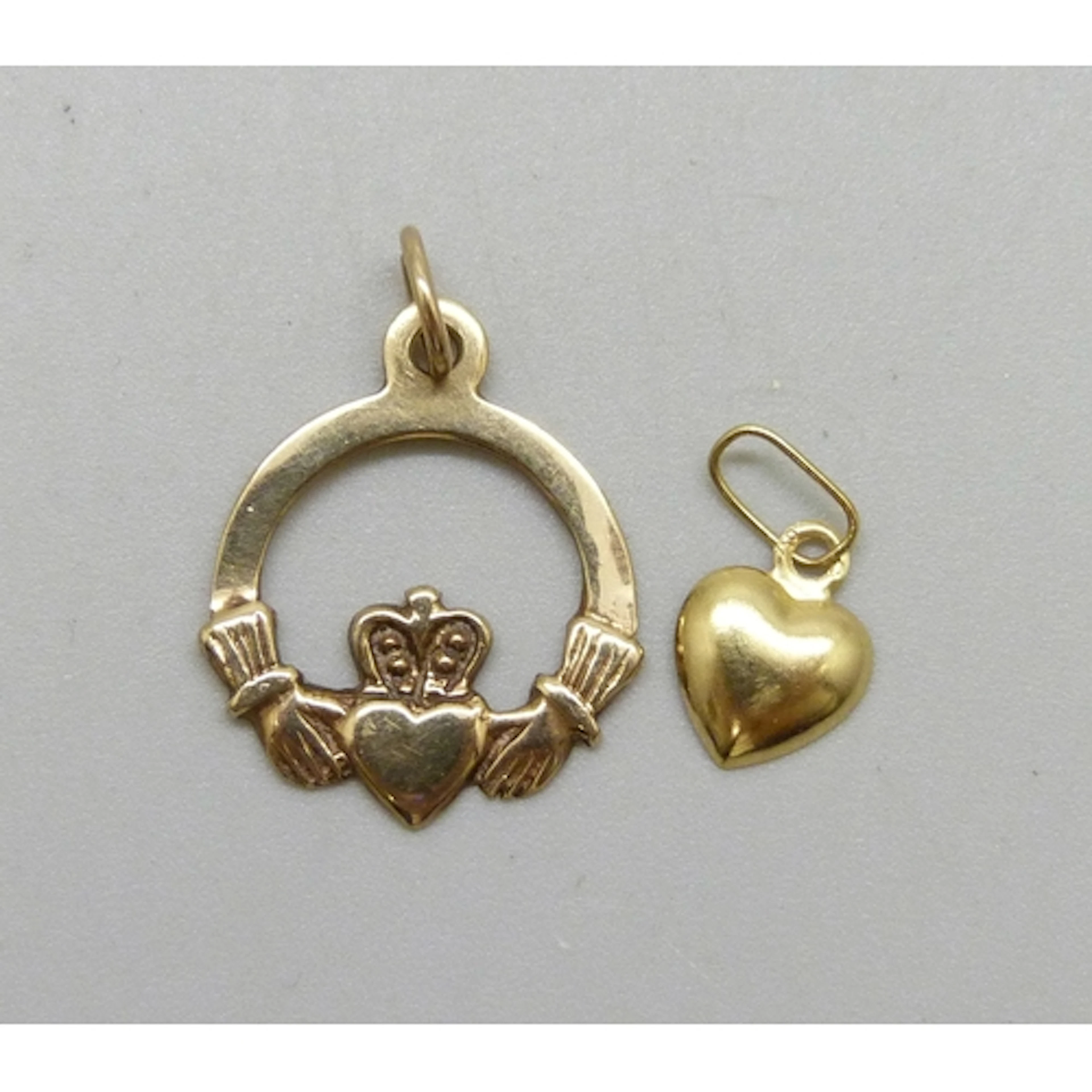 A 9ct gold claddagh pendant, and a yellow metal heart charm,...