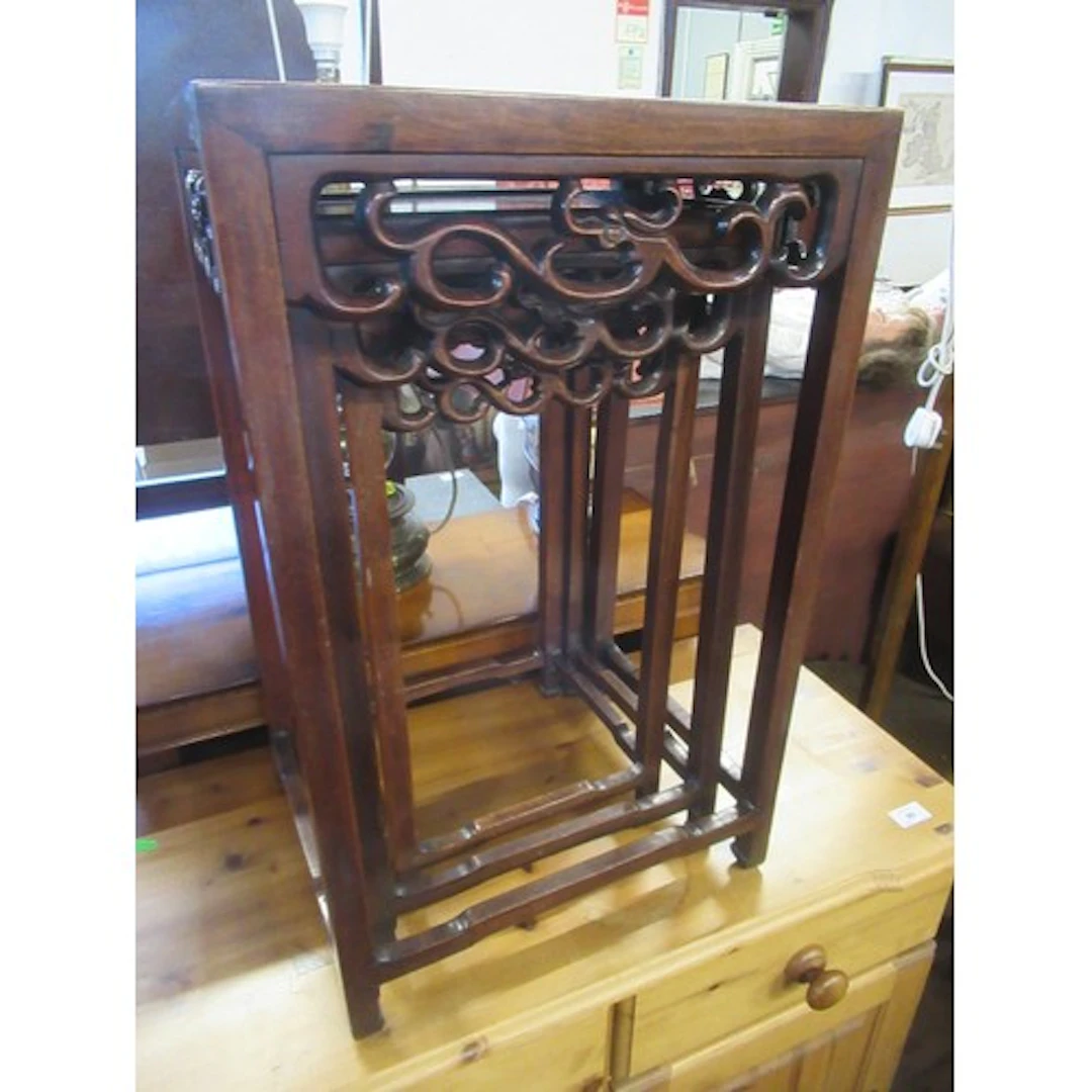 An oriental hardwood nest of three tables with carved frieze...