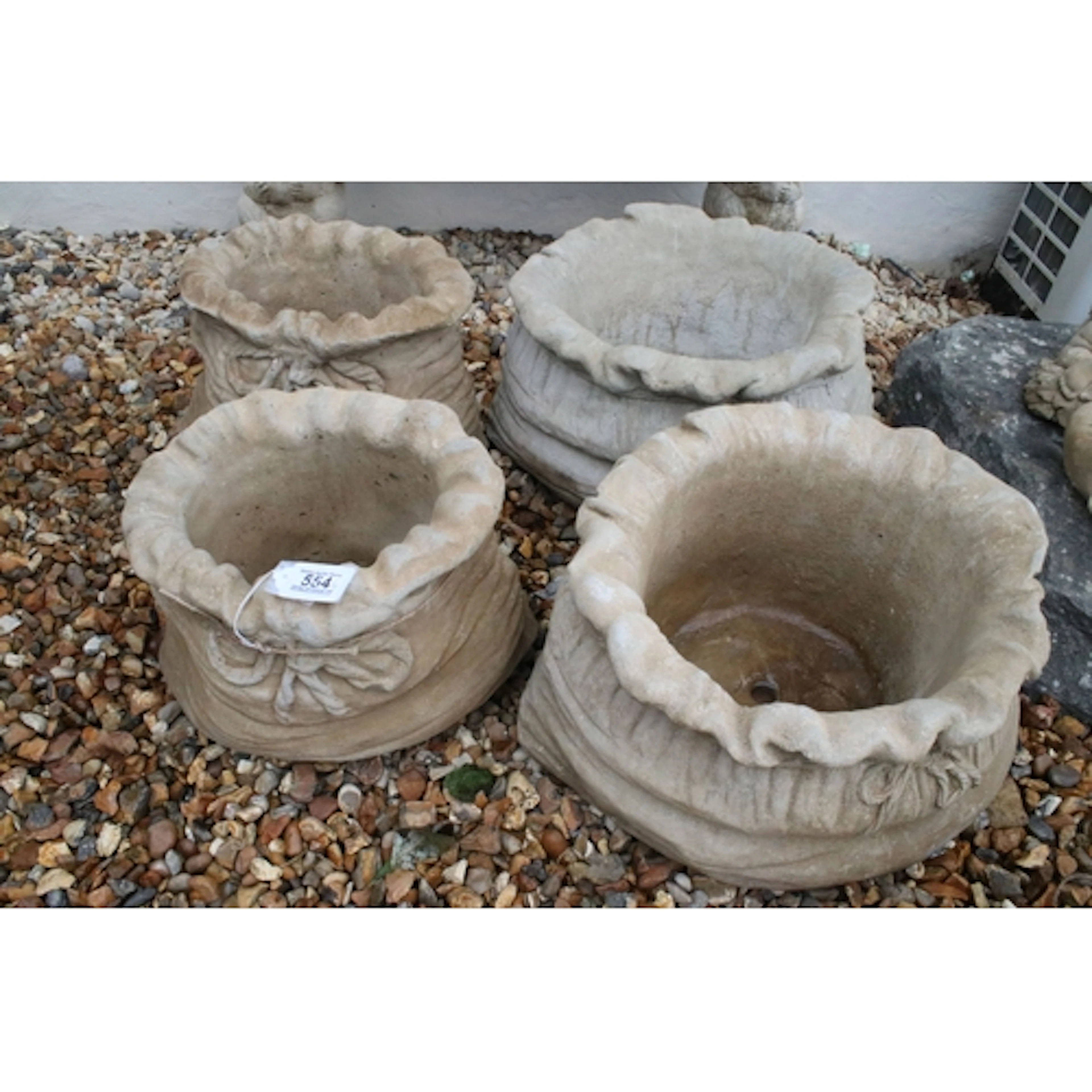 Group of four reconstituted stone sack planters, in the form...