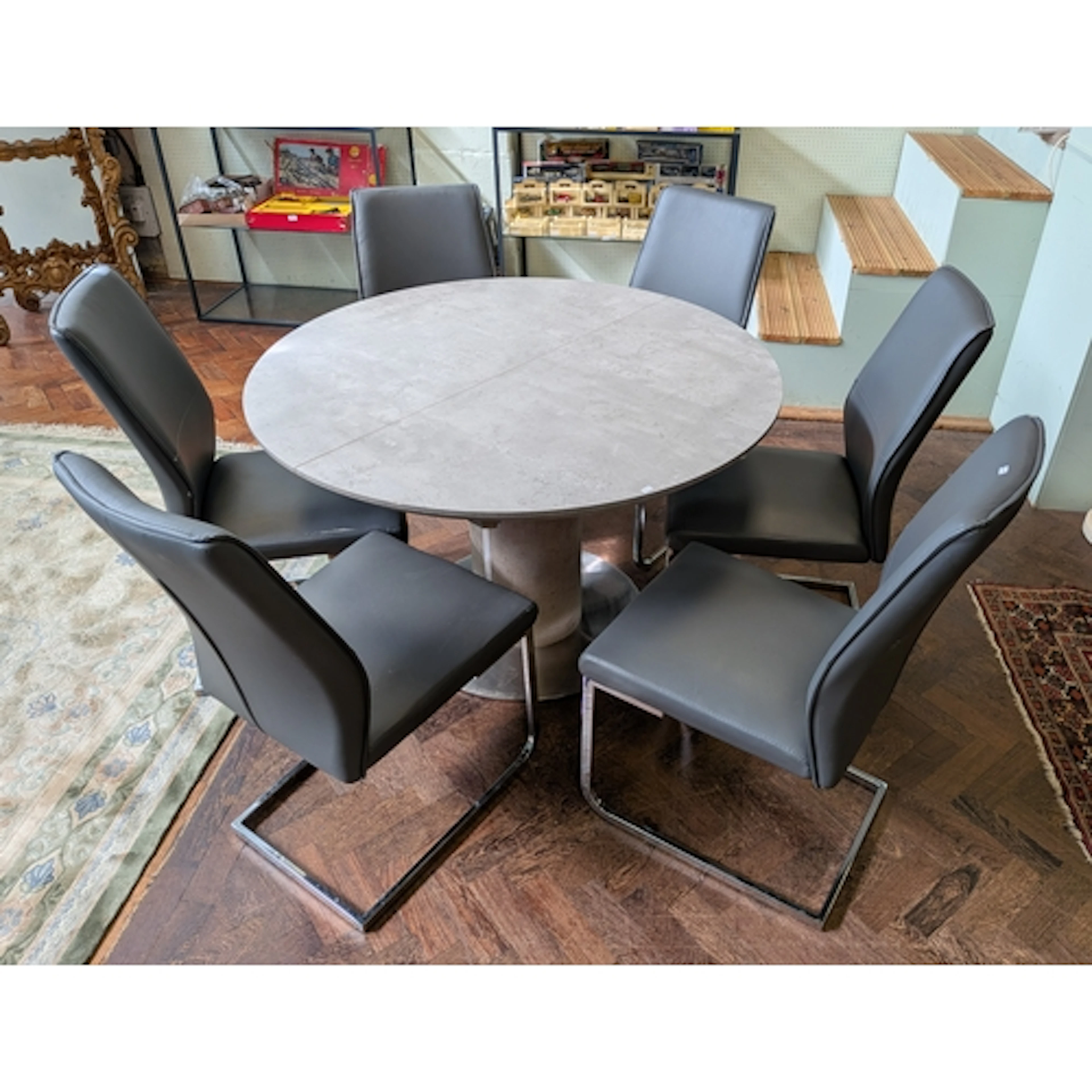 A modern chrome framed circular granite style grey dining ta...