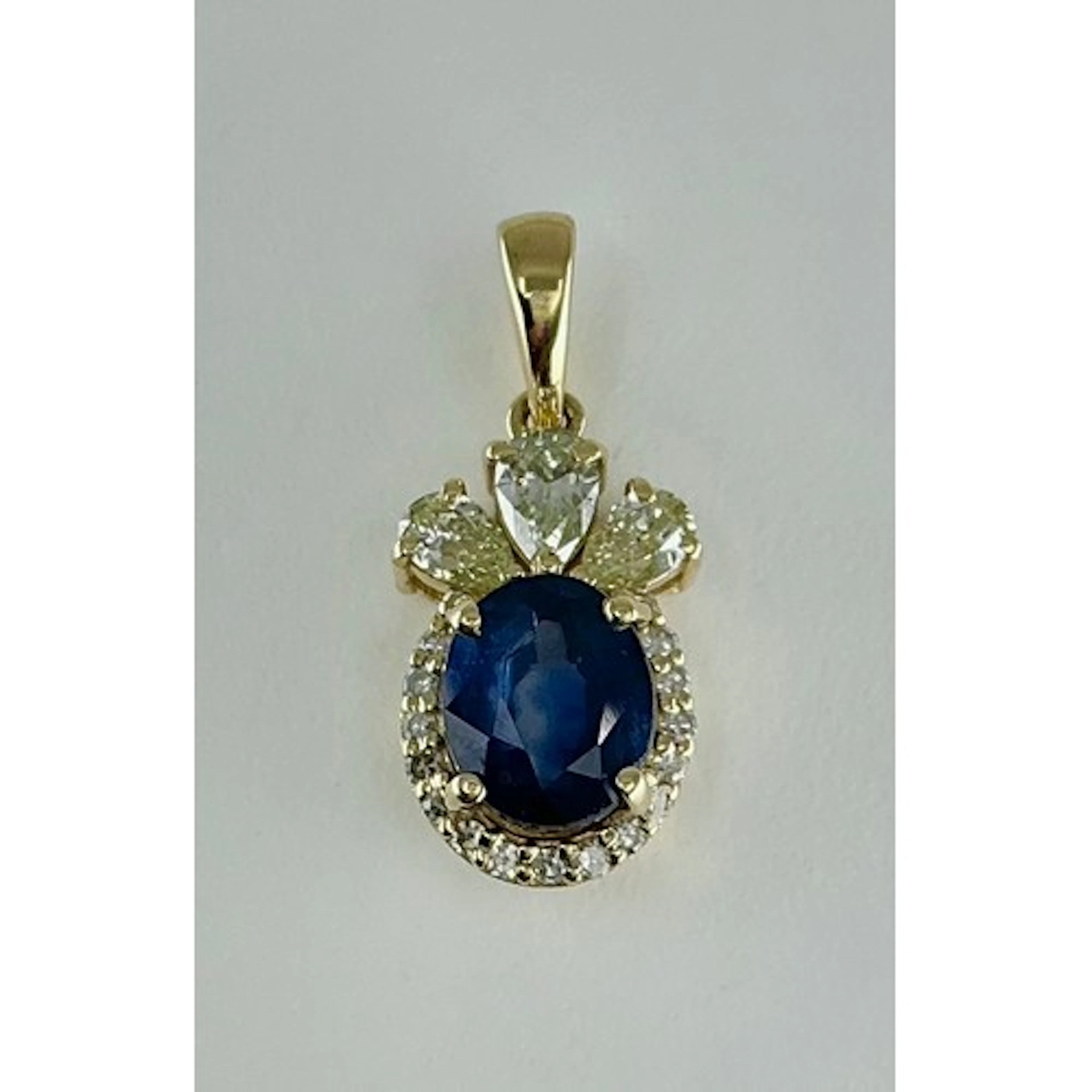 A sapphire and diamond cluster pendant, central blue oval mi...
