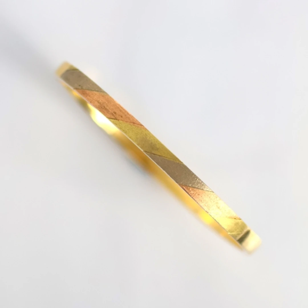 A continental yellow metal bangle, the textured front with t...