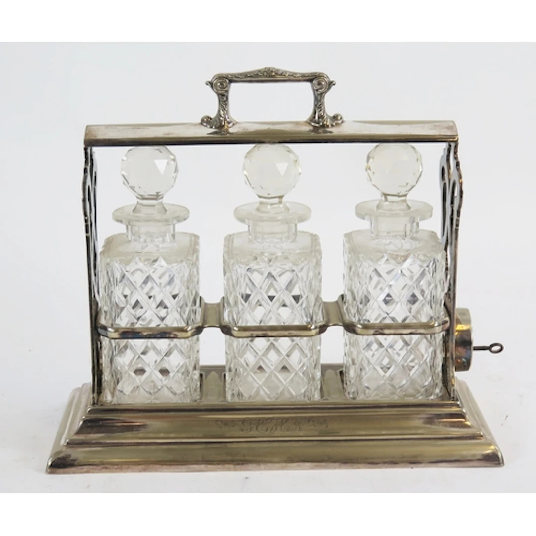 A silver plated tantalus containing three clear glass decant...
