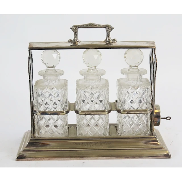 A silver plated tantalus containing three clear glass decant...