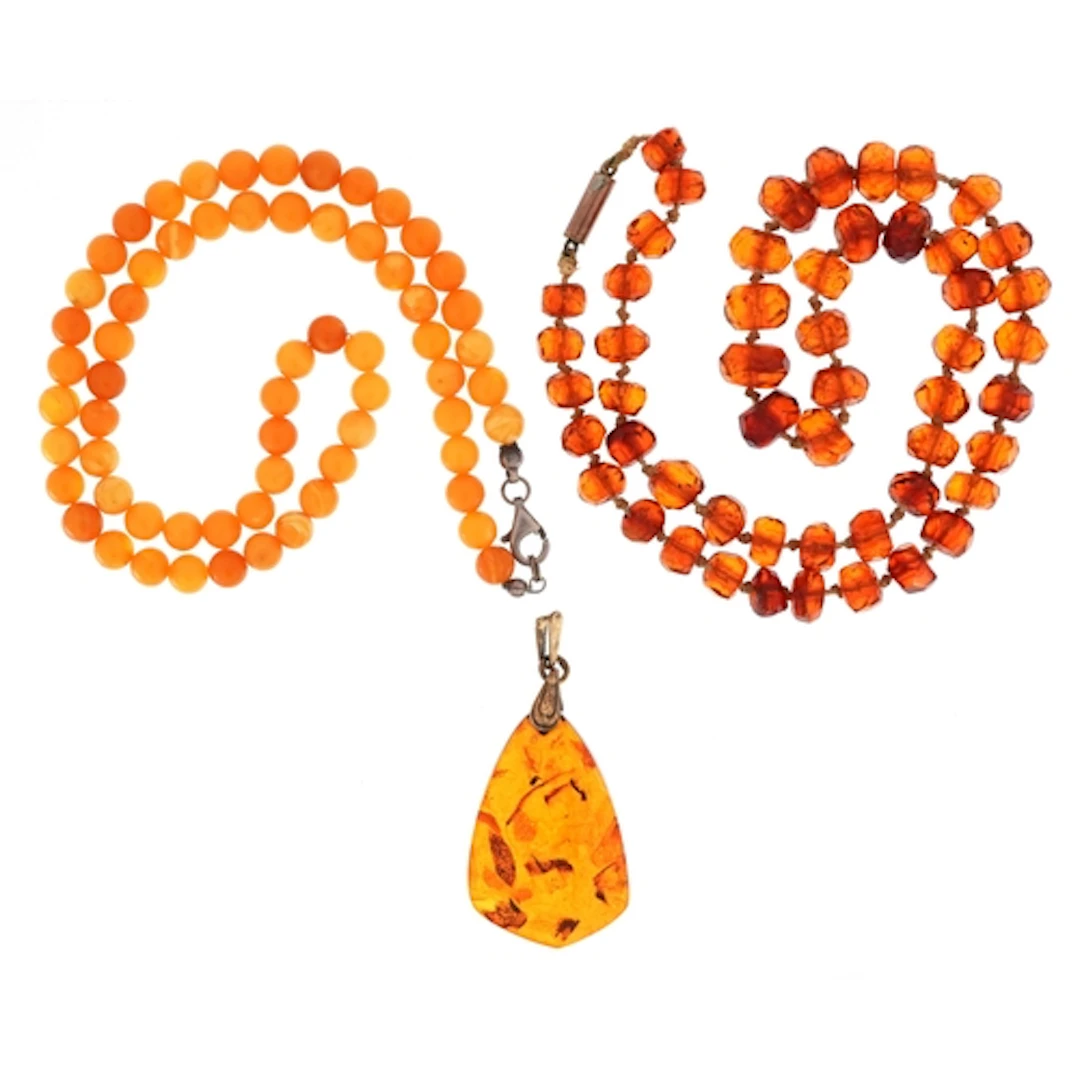 Two amber coloured bead necklaces and a natural amber pendan...