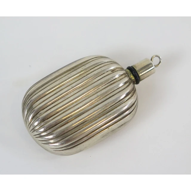 A white metal scent bottle of oval form, with reeded decorat...