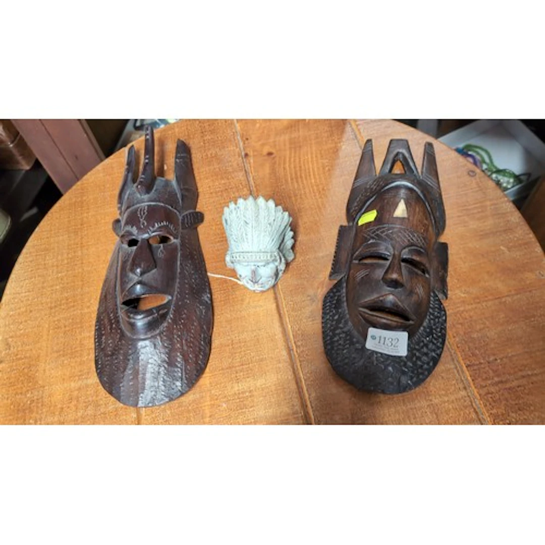 Two carved wooden masks with pierced features and projecting...