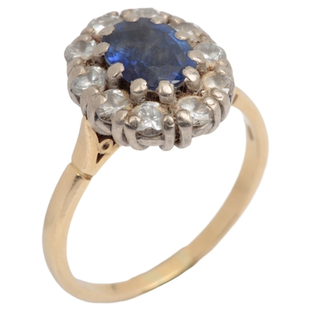A sapphire and diamond cluster ring, claw-set with an oval s...