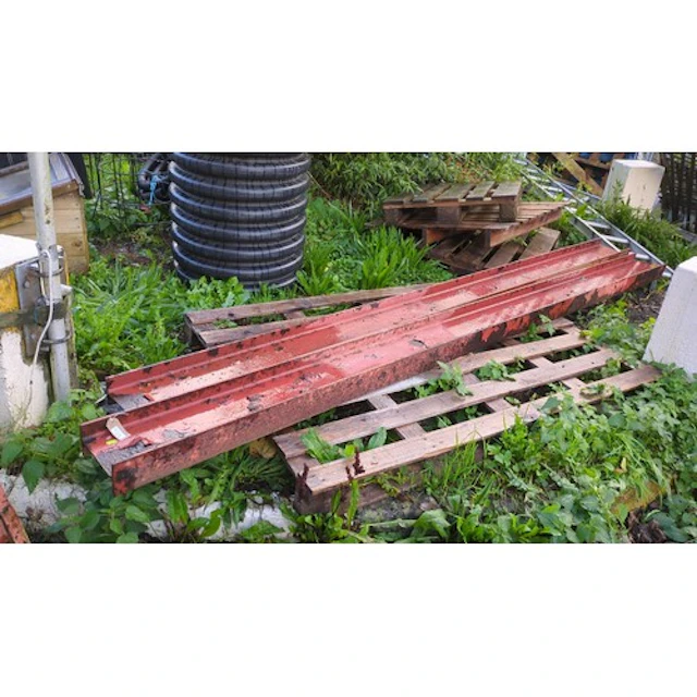 A pair of long red-painted steel channel sections with raise...