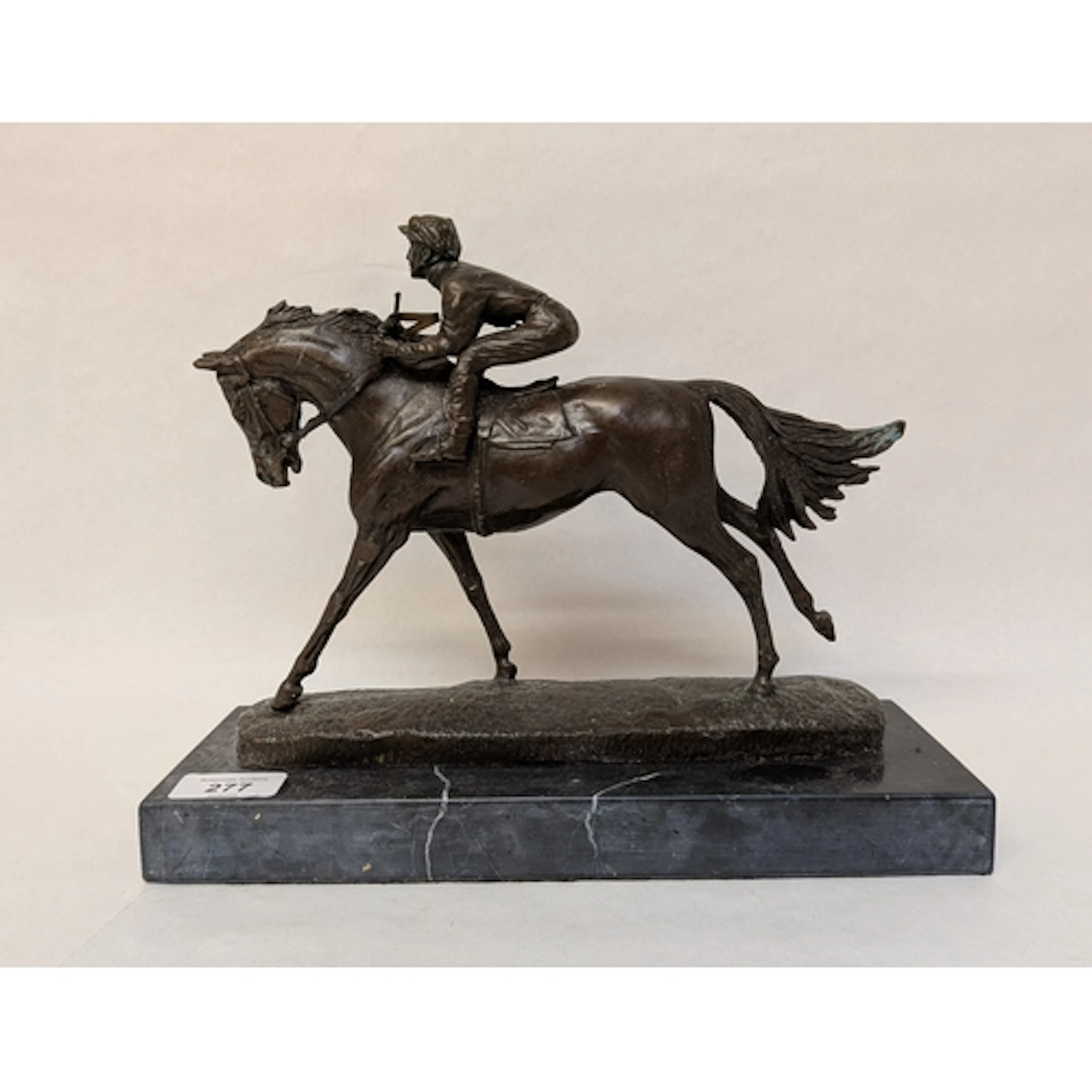 A bronze figure of a race horse and jockey, mounted on a bla...