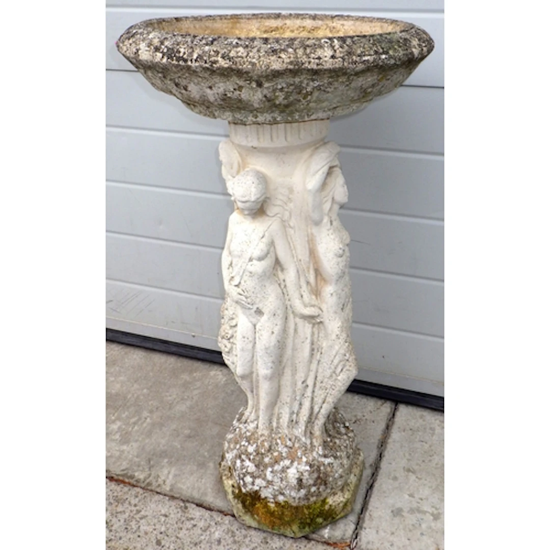 A concrete bird table on a figural base, 78cm tall