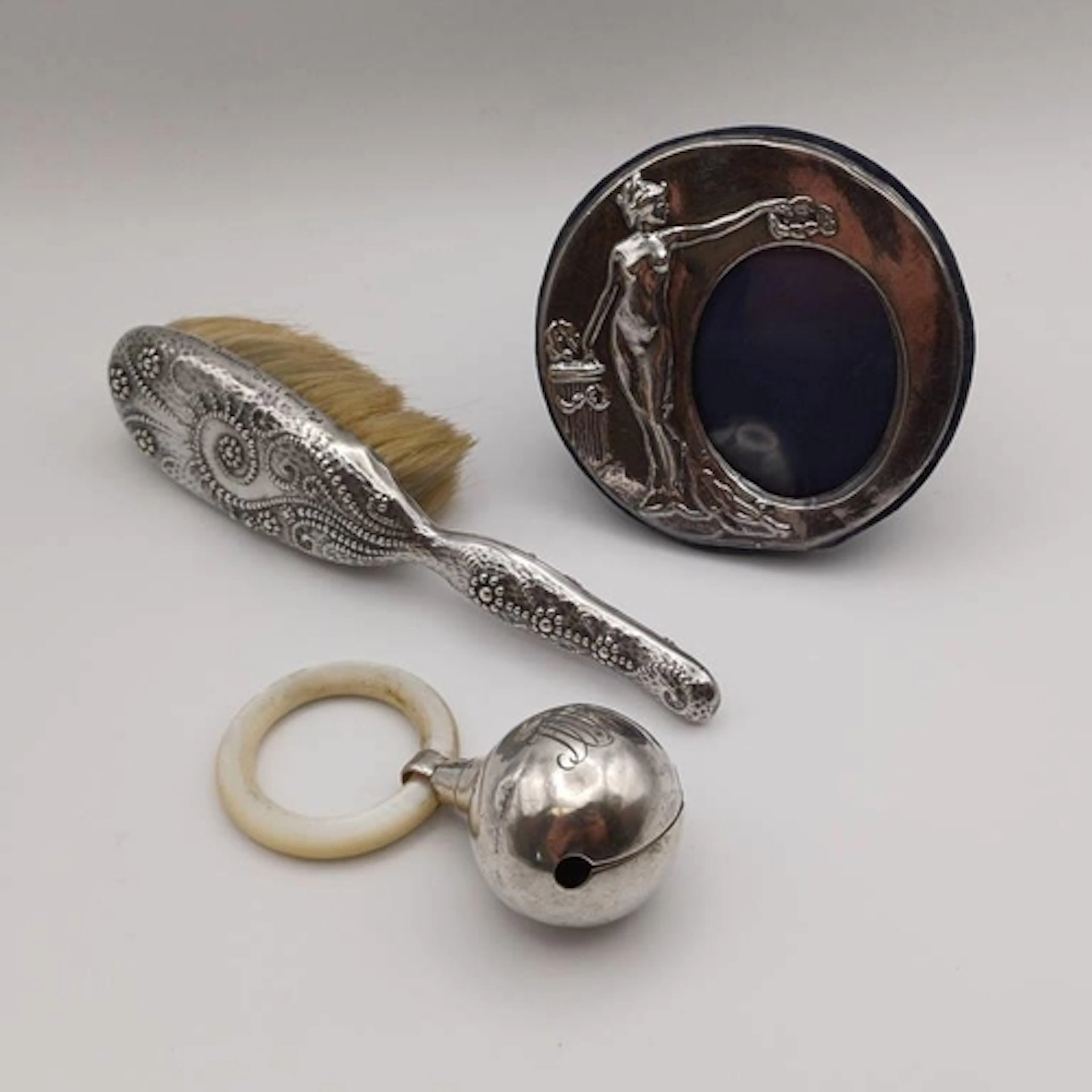 A SMALL SILVER PHOTO FRAME EMBOSSED WITH GREEK FIGURE. AN AM...