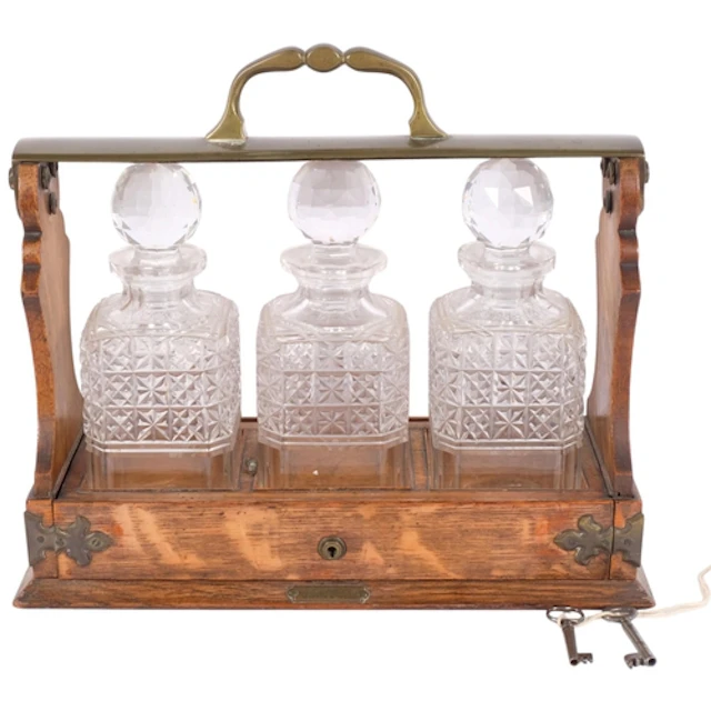 An oak 3-bottle tantalus with metal mounts, 35cm across