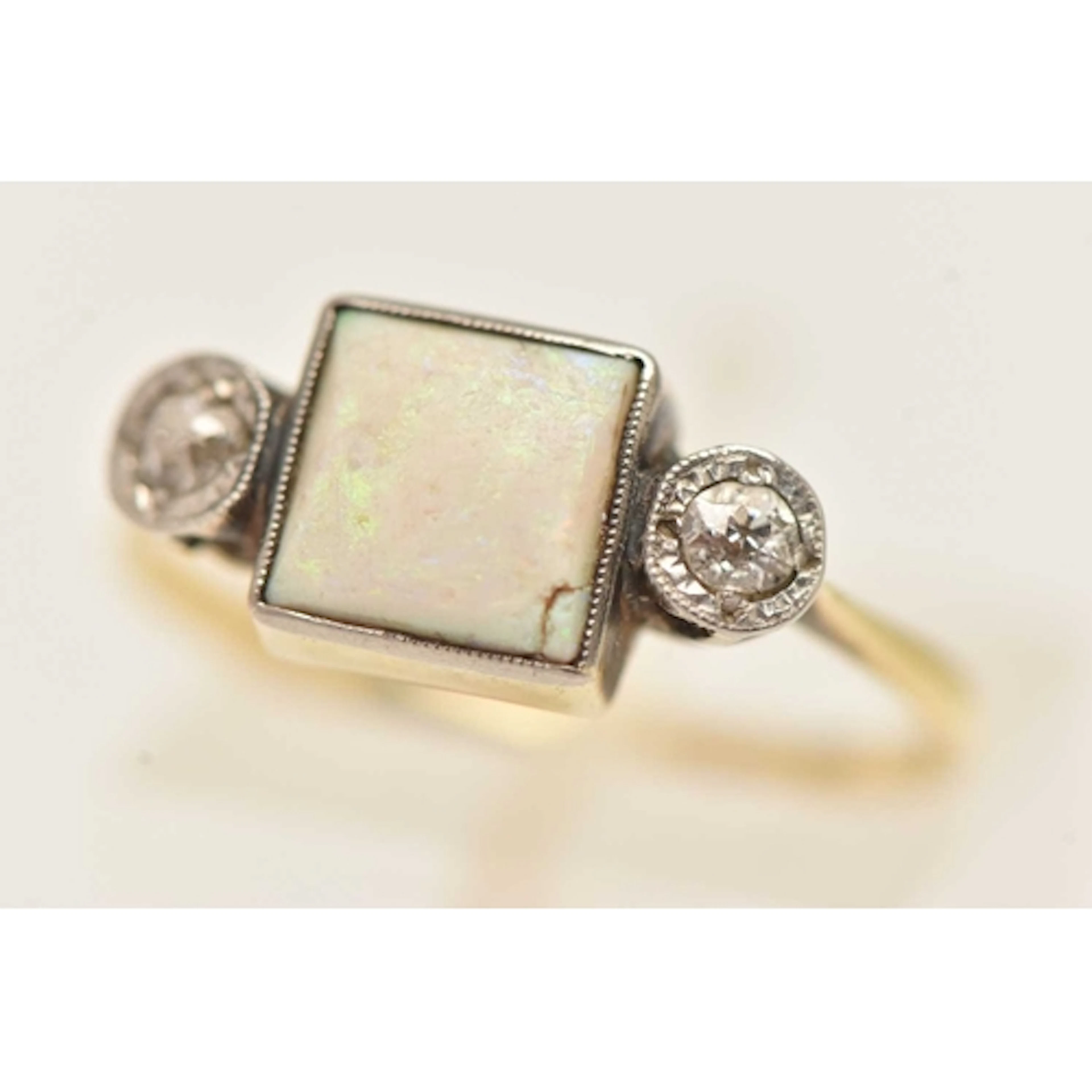 A GEM SET RING, a square cabochon opal, flanked with two ill...
