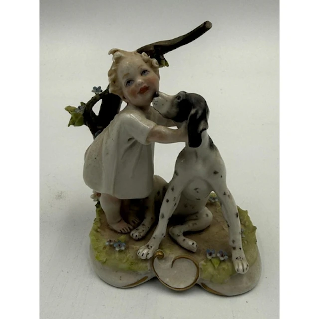 A small Capo di Monte figure of a child with her dog. ...