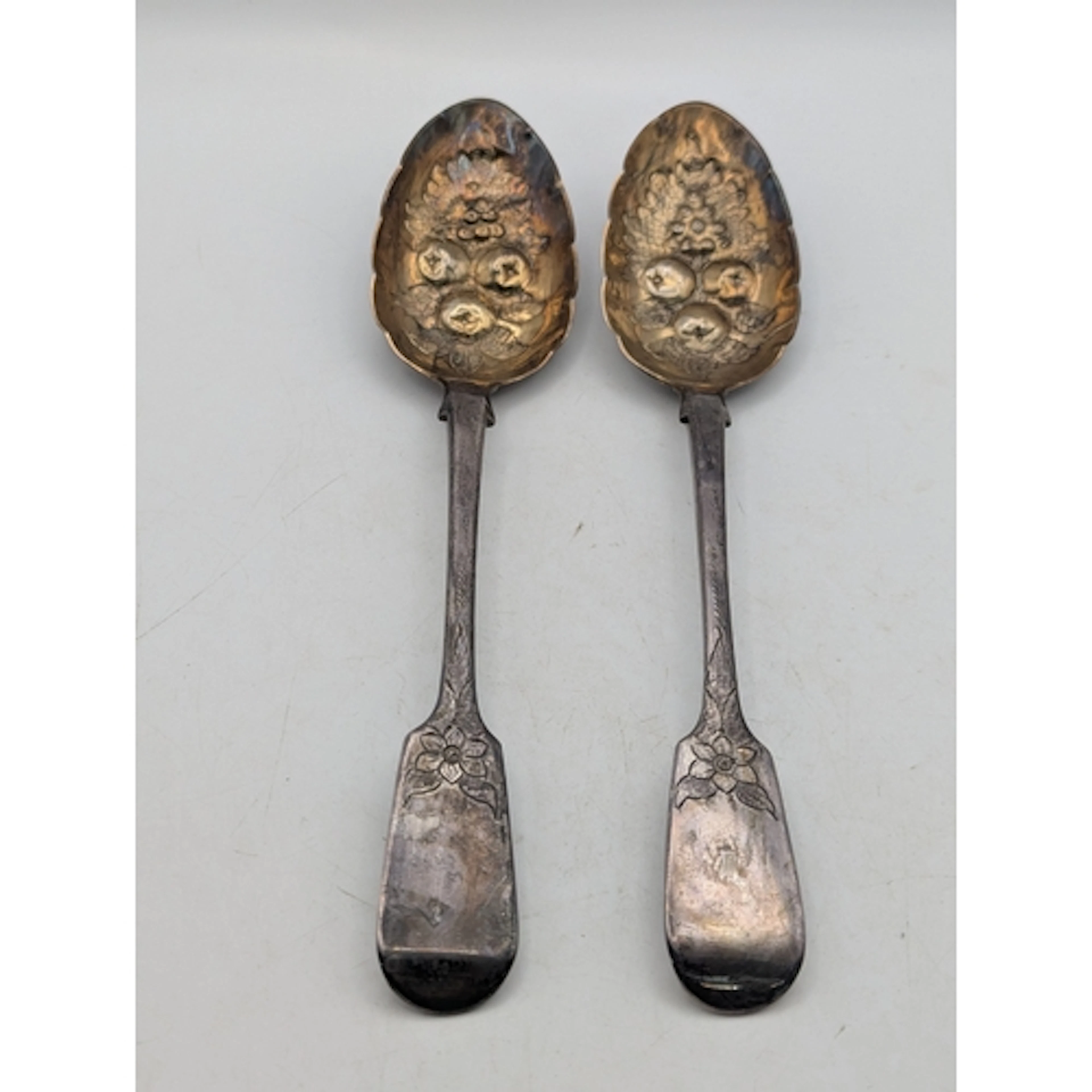 A pair of Victorian silver berry spoons having floral engrav...