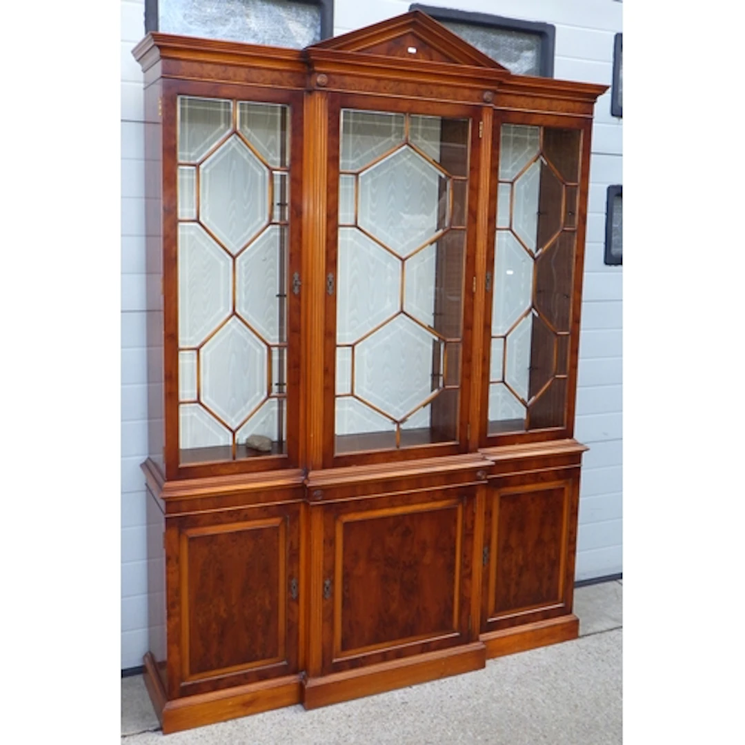 A reproduction yew three door bookcase with bevelled glass, ...