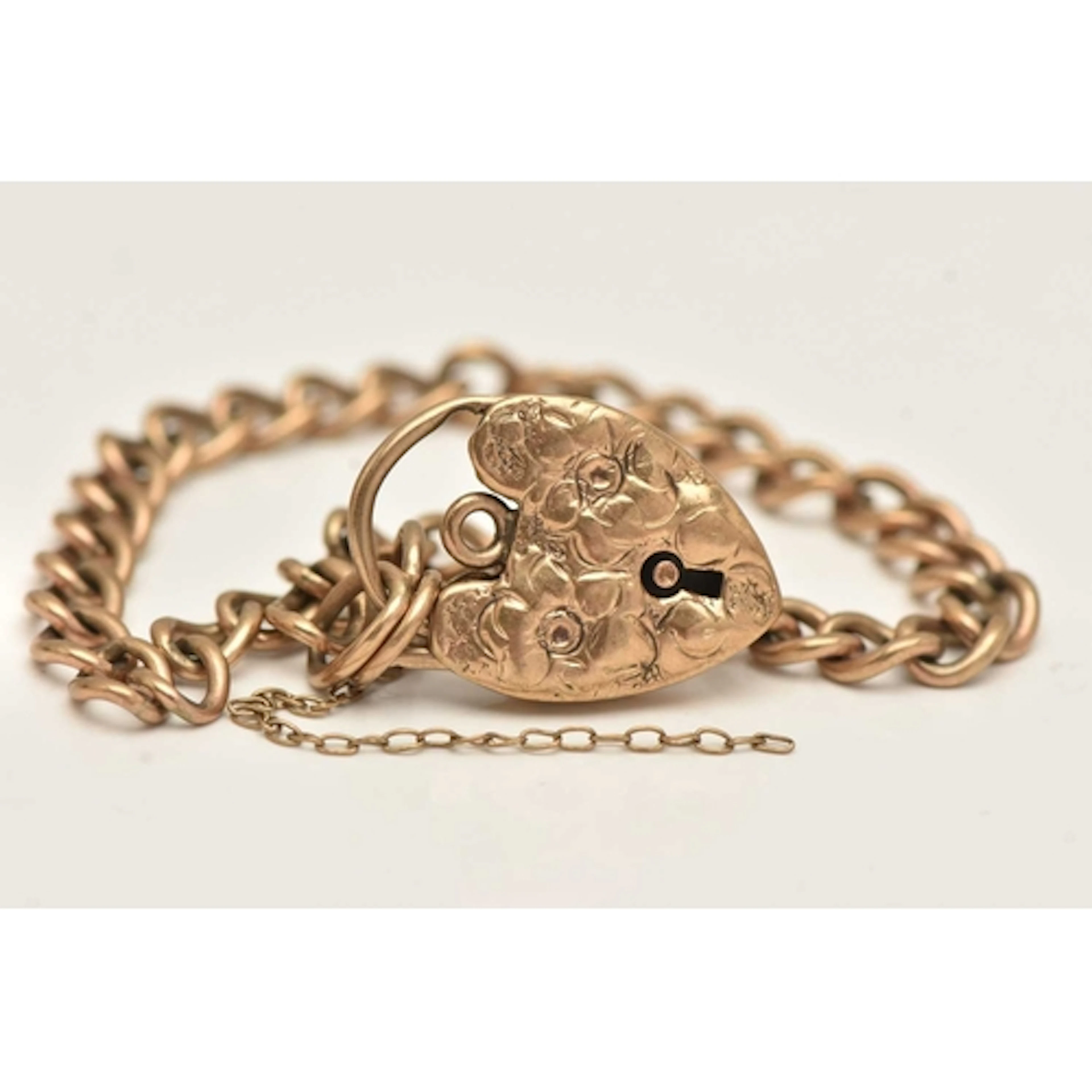 A 9CT GOLD CURB LINK BRACELET, fitted with a heart padlock c...