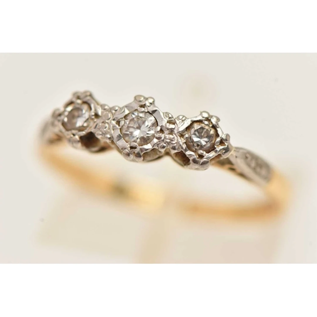 AN 18T GOLD THREE STONE DIAMOND RING, three small round bril...