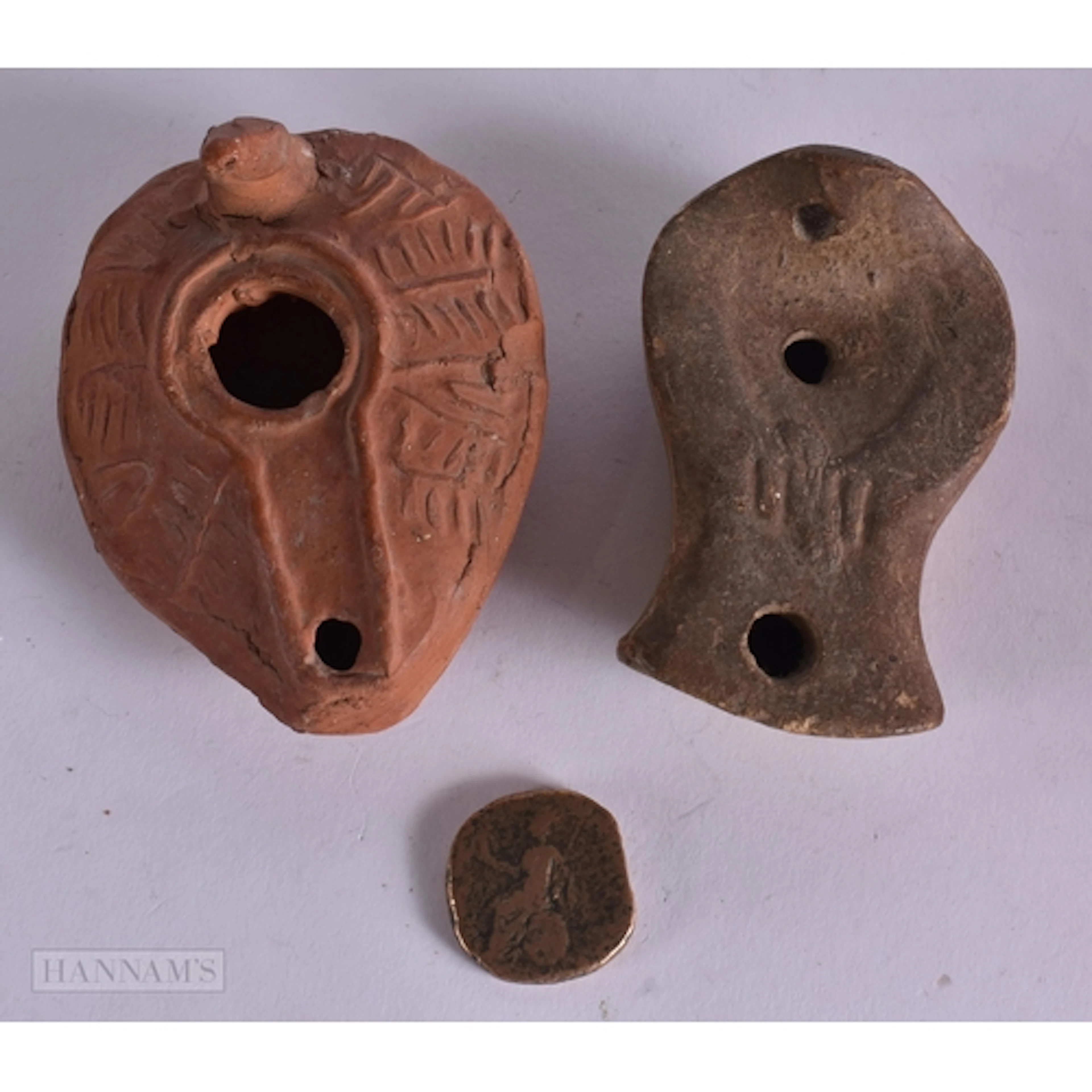 TWO EARLY OIL LAMPS possibly antiquity and a coin. (3)
