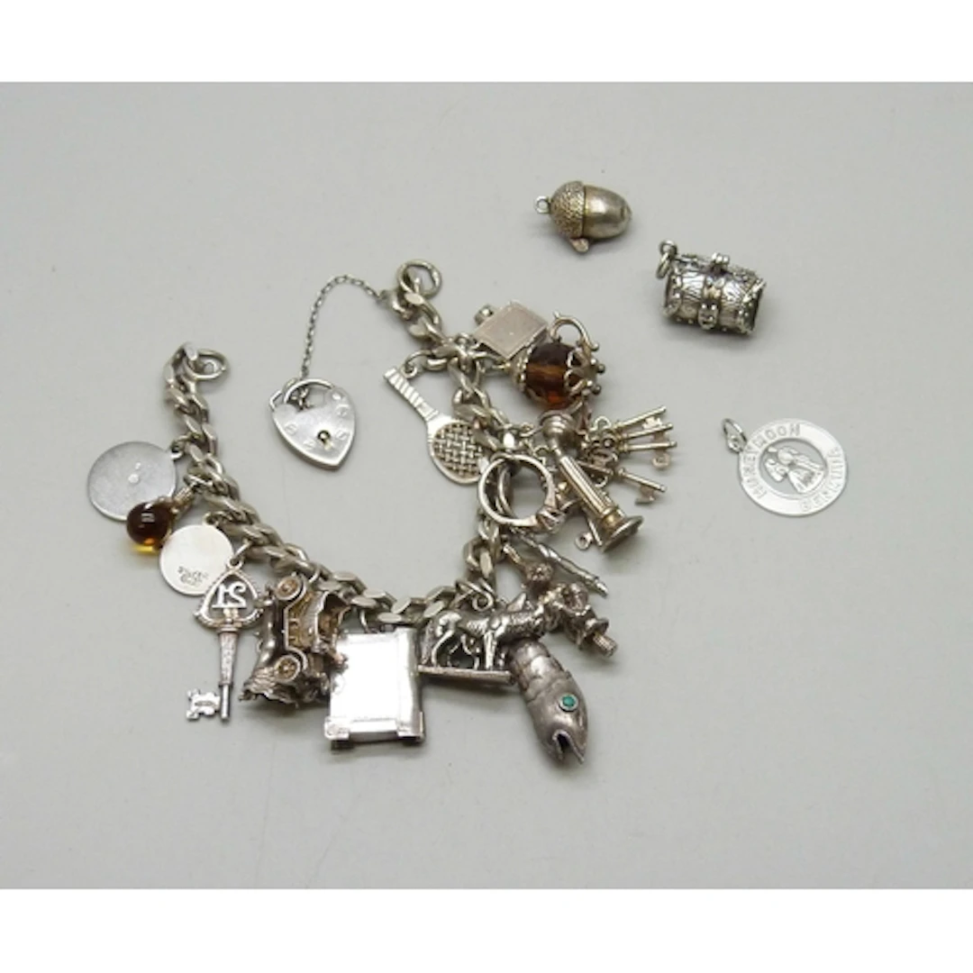 A silver charm bracelet with a collection of silver and whit...