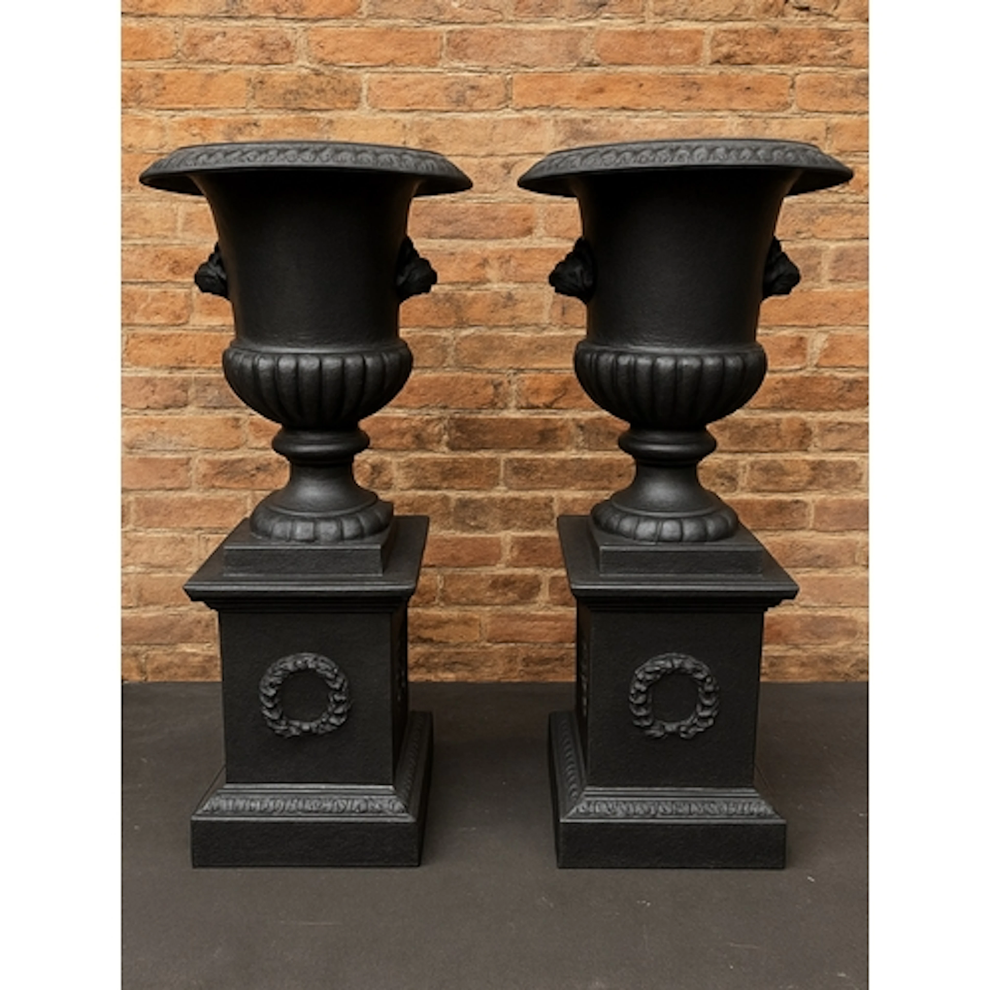 A pair of handsome cast iron campana urns on pedestal stands...