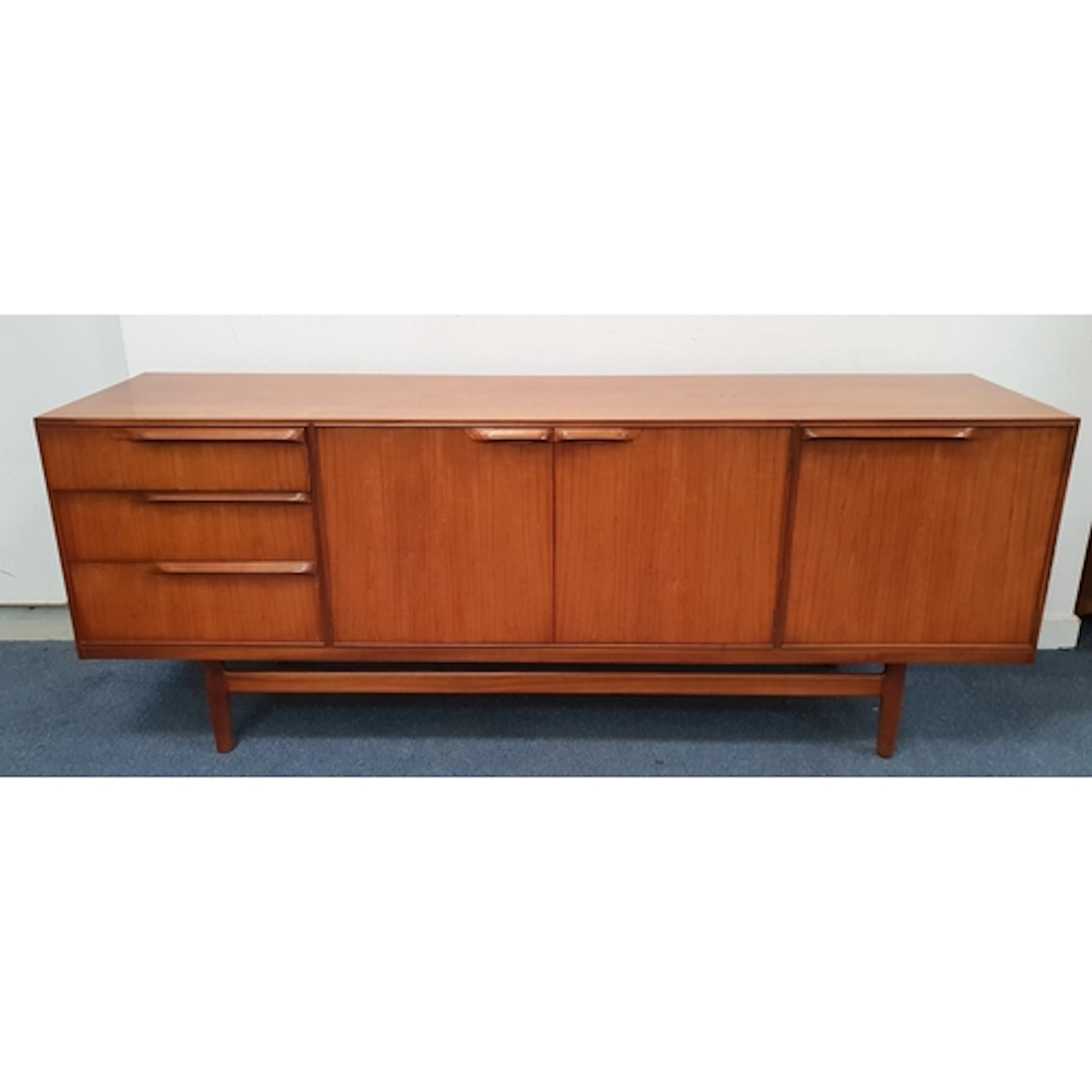 MID-CENTURY TEAK SIDEBOARD with a bank of three graduated dr...