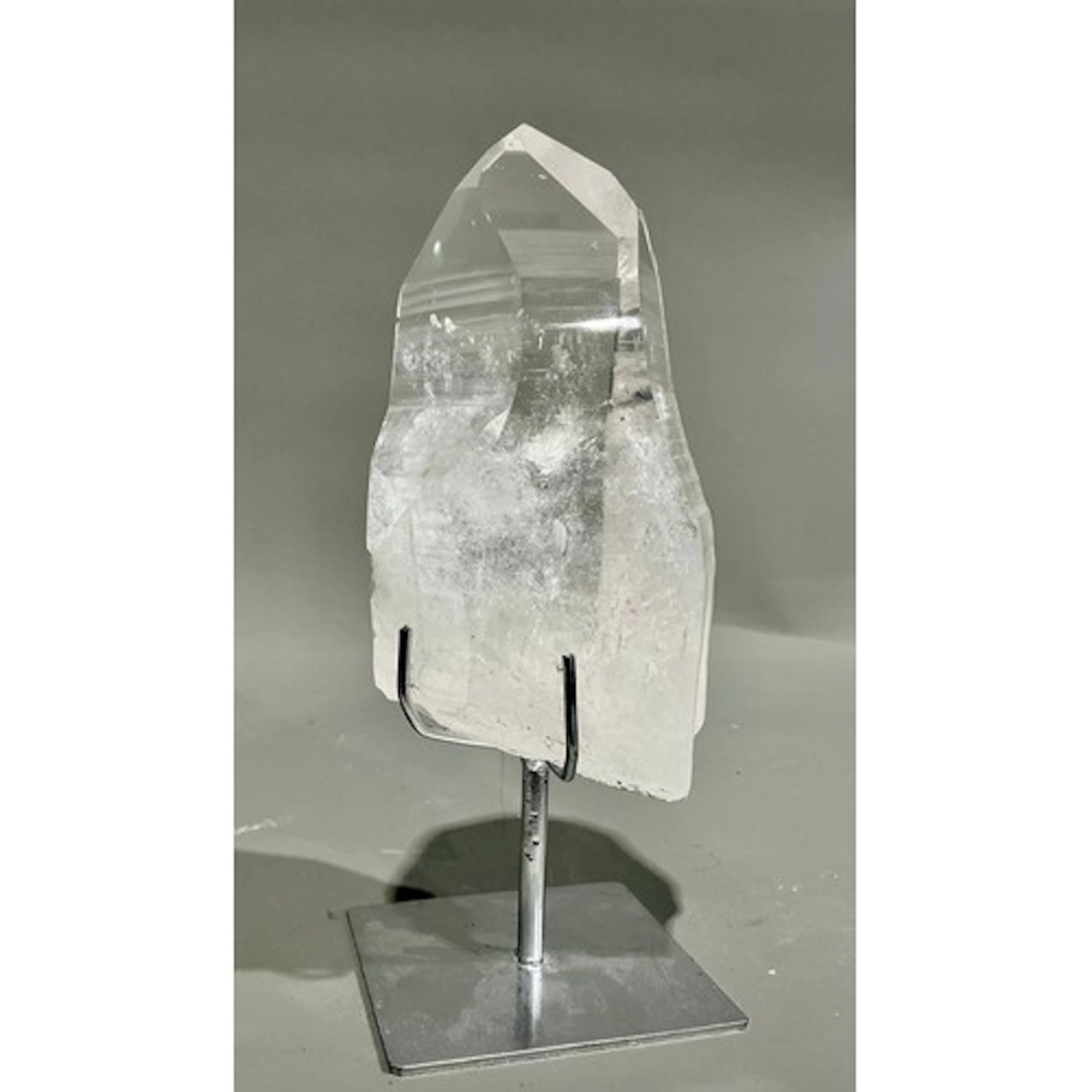 A large polished clear Brazilian quartz point on stand, rain...