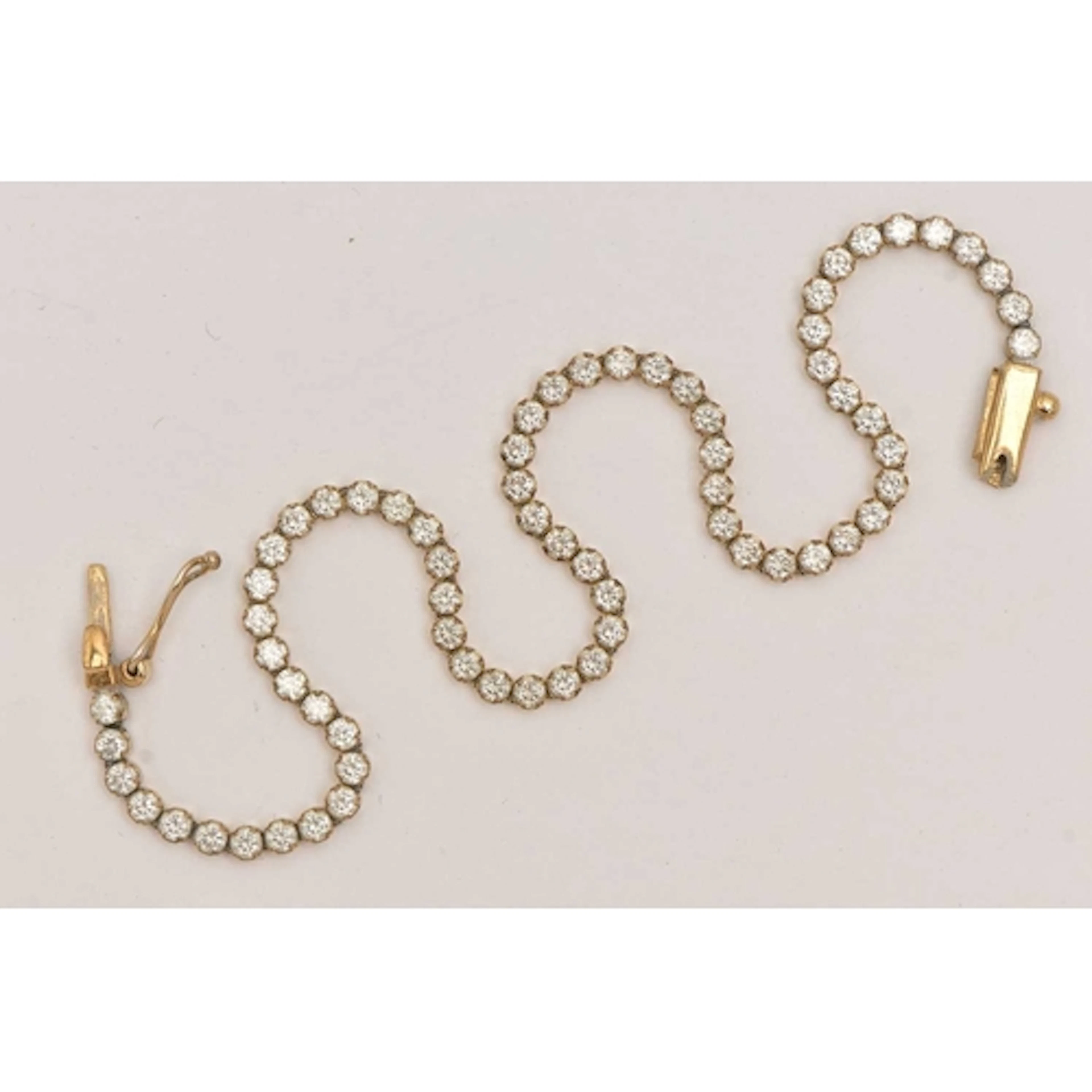 A YELLOW METAL CUBIC ZIRCONIA TENNIS BRACELET, designed as a...