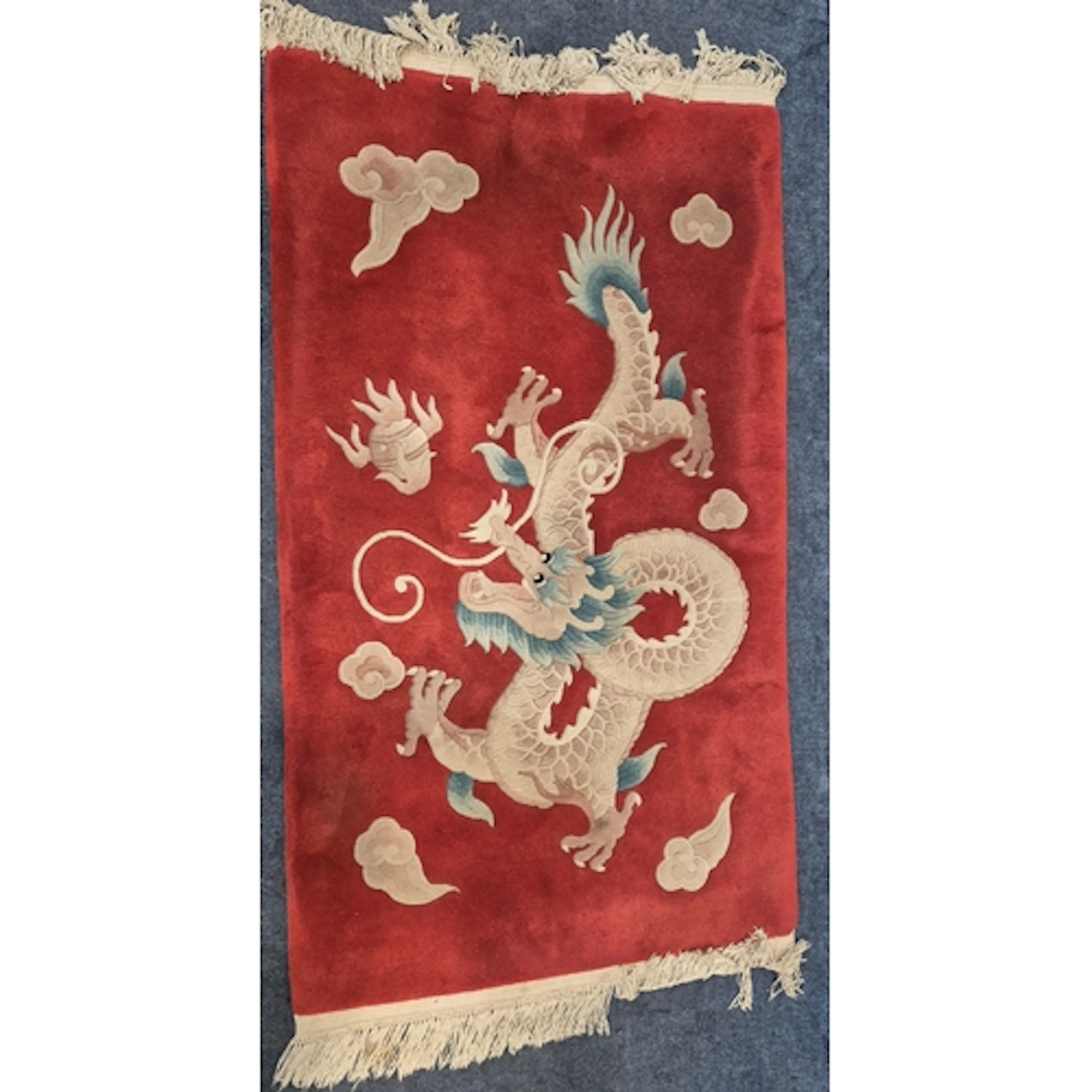 A RED GROUND CHINESE WOOLEN RUG, depicting a mythical creatu...