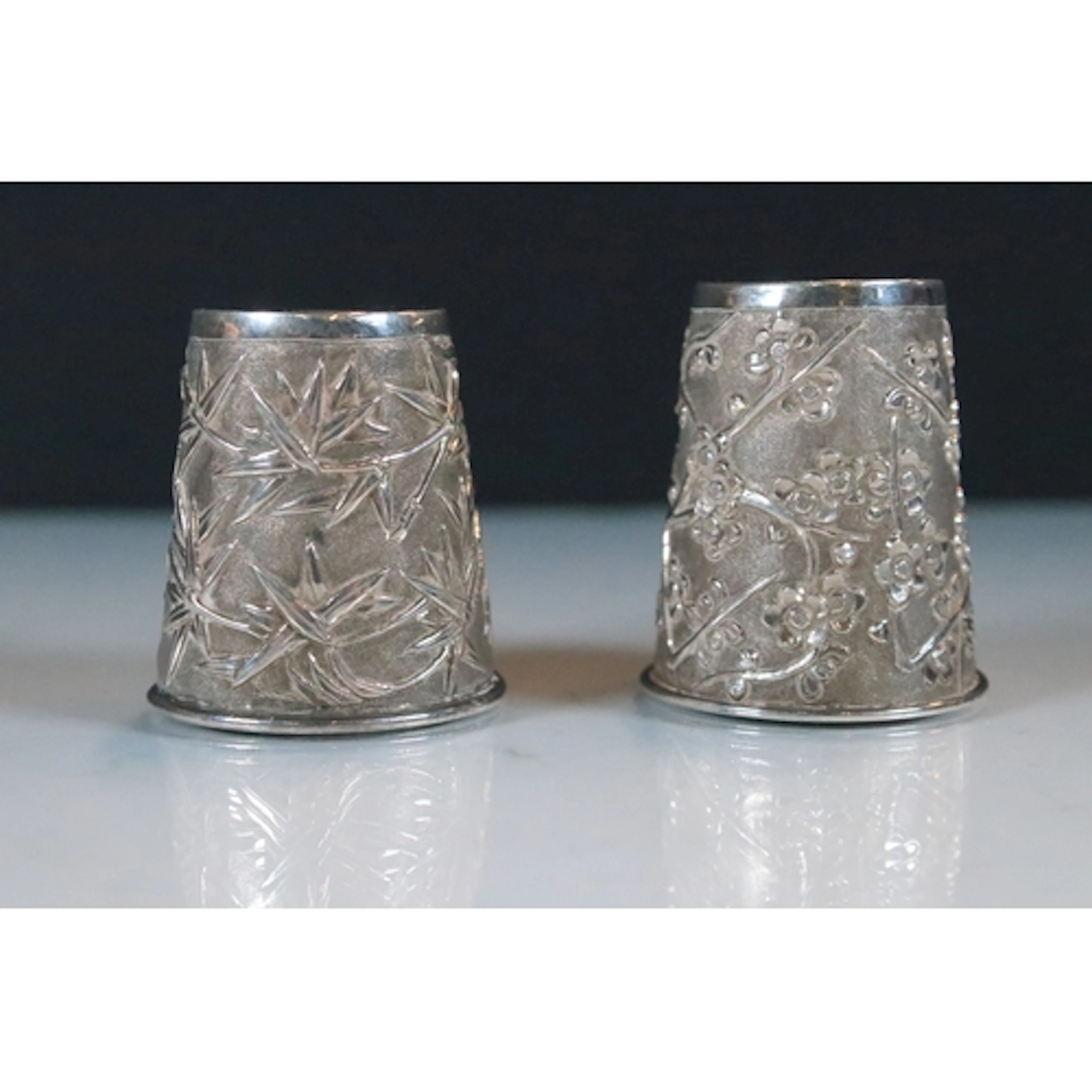 Two Chinese silver miniature beakers featuring prunus and ba...